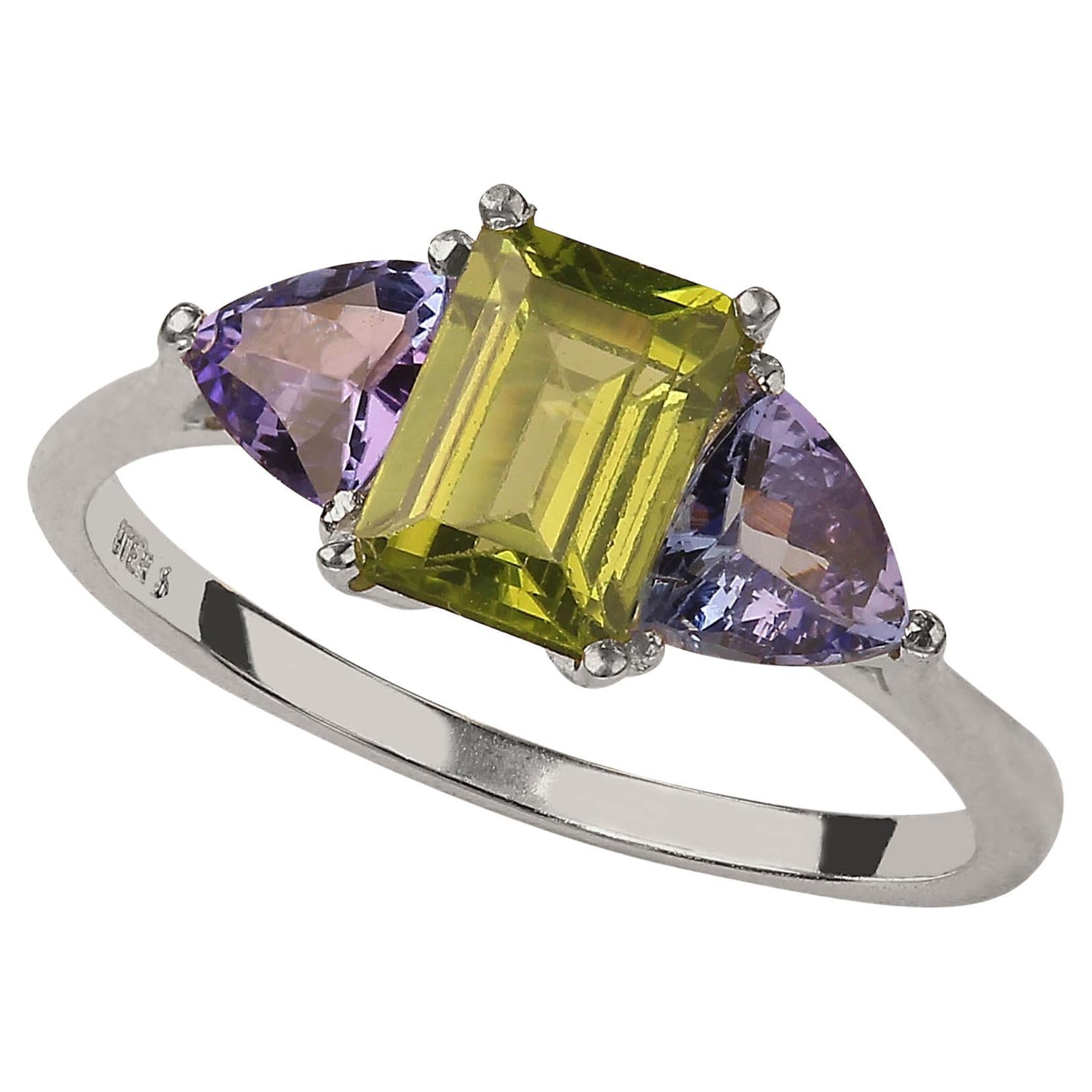 Delightful ring of emerald cut sparkling Peridot accented with triangles of glittering Tanzanites. Wear these gems with everything and enjoy how the green and purple works with your entire wardrobe.  The emerald cut Peridot is approximately 1.30