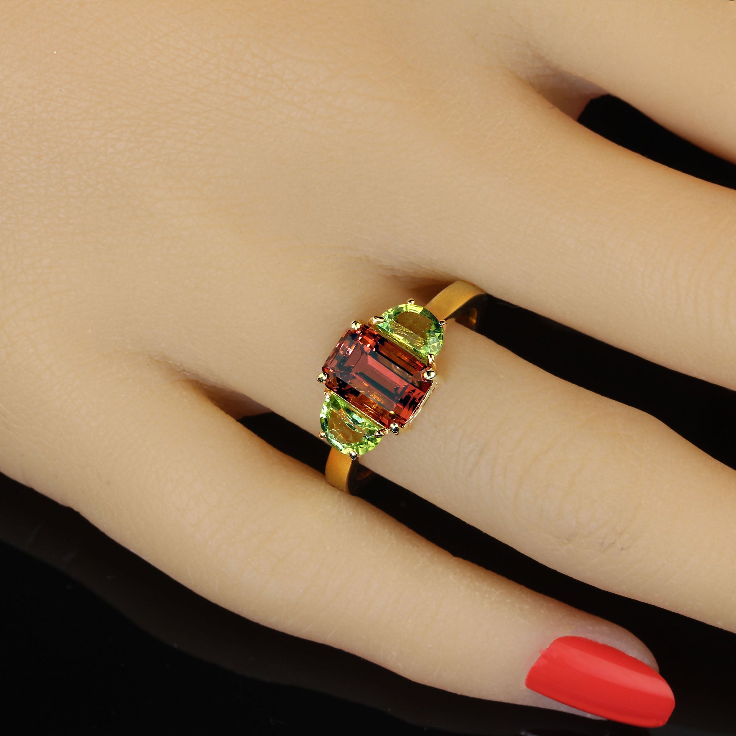 Découvrez la beauté rare de cette superbe bague en tourmaline orange, rehaussée de deux péridots en demi-lune, le tout serti dans un luxueux rhodium d'or sur argent sterling. Cette tourmaline orange étincelante de 2,70ct, provenant des montagnes à