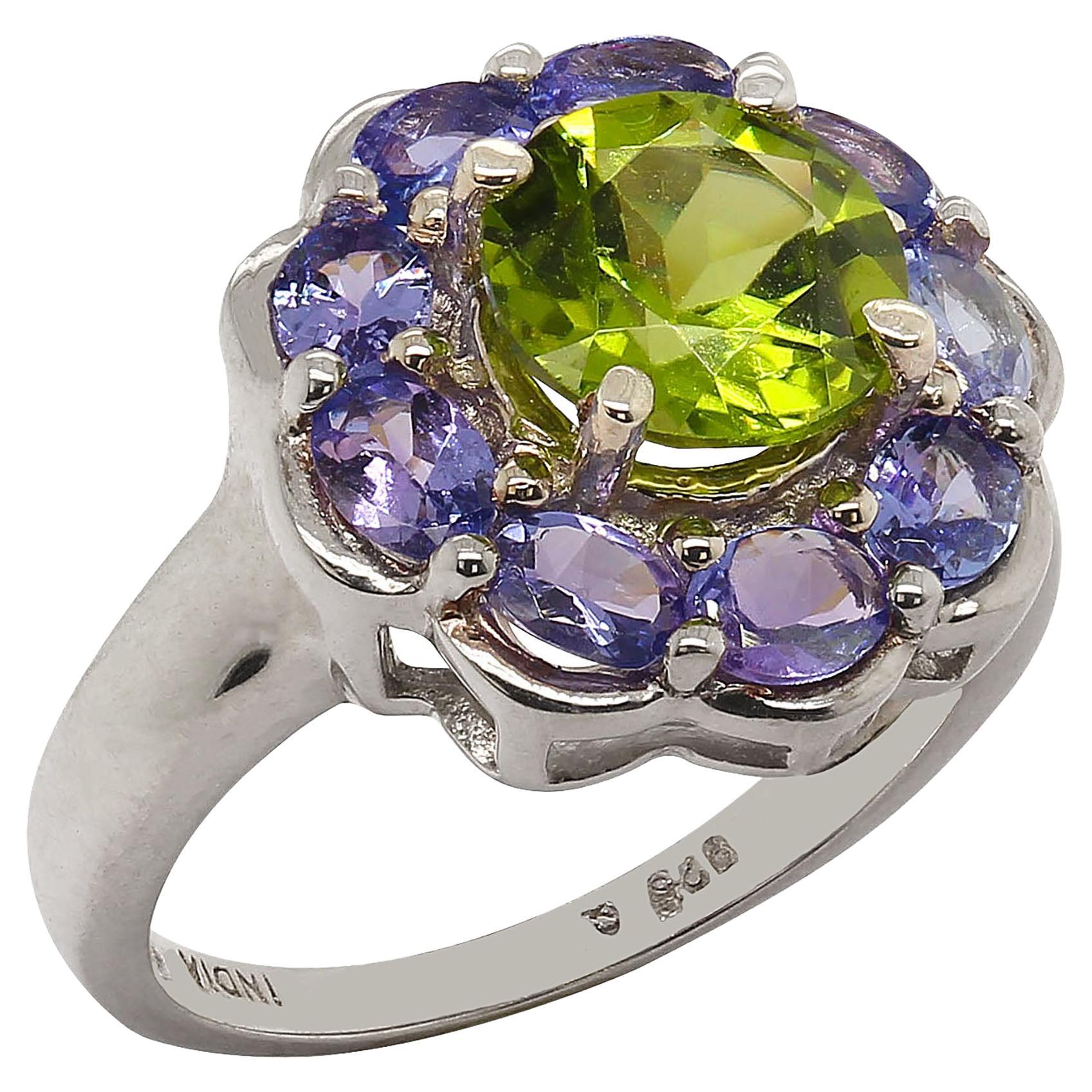 Gorgeous Cocktail ring featuring a lively round bright green Peridot (2ct) encircled by a halo of sparkling round Tanzanites (1.44ct). This lovely ring sparkles and dances as you move your hand.  It is a size 7, please select carefully as it is