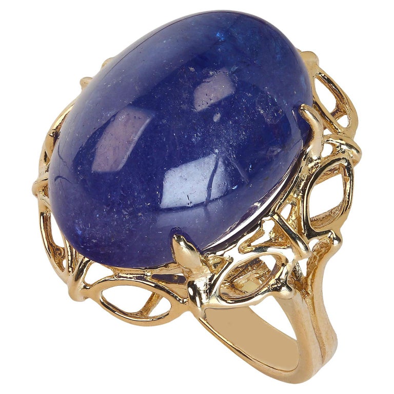 Feast your eyes on this gorgeous glowing 27 carat oval Tanzanite cabochon neslted in a lacy 14K yellow gold setting.  This 14K yellow gold setting perfectly complements the large velvety Tanzanite.  This is a sizable 7.5. No sizing available by