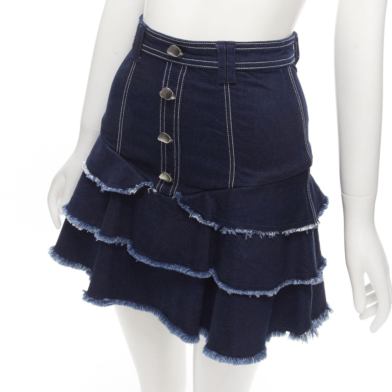 AJE hammered silver buttons blue frayed edge tiered denim skirt UK6 XS
Reference: AAWC/A00442
Brand: Aje
Material: Denim
Color: Blue
Pattern: Solid
Closure: Zip Fly
Made in: China

CONDITION:
Condition: Excellent, this item was pre-owned and is in