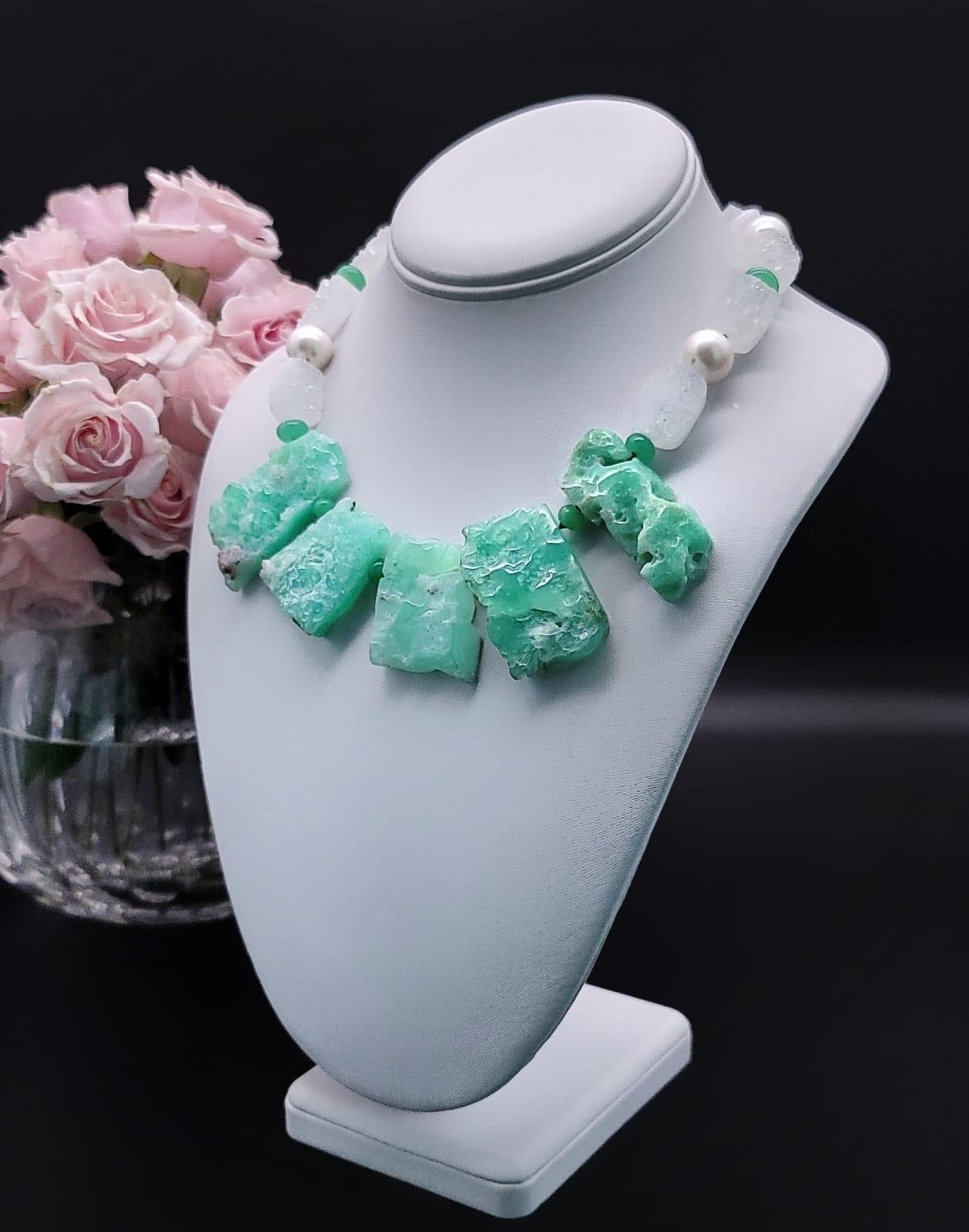 
One-of-a-Kind

As fresh and cooling as a mint julep. A bib of specimen Chrysoprase geodes is cut as a set to show off the usual markings and polished on the back to the familiar green. The strand surrounding the bib are sugar cubes of crystal druzy