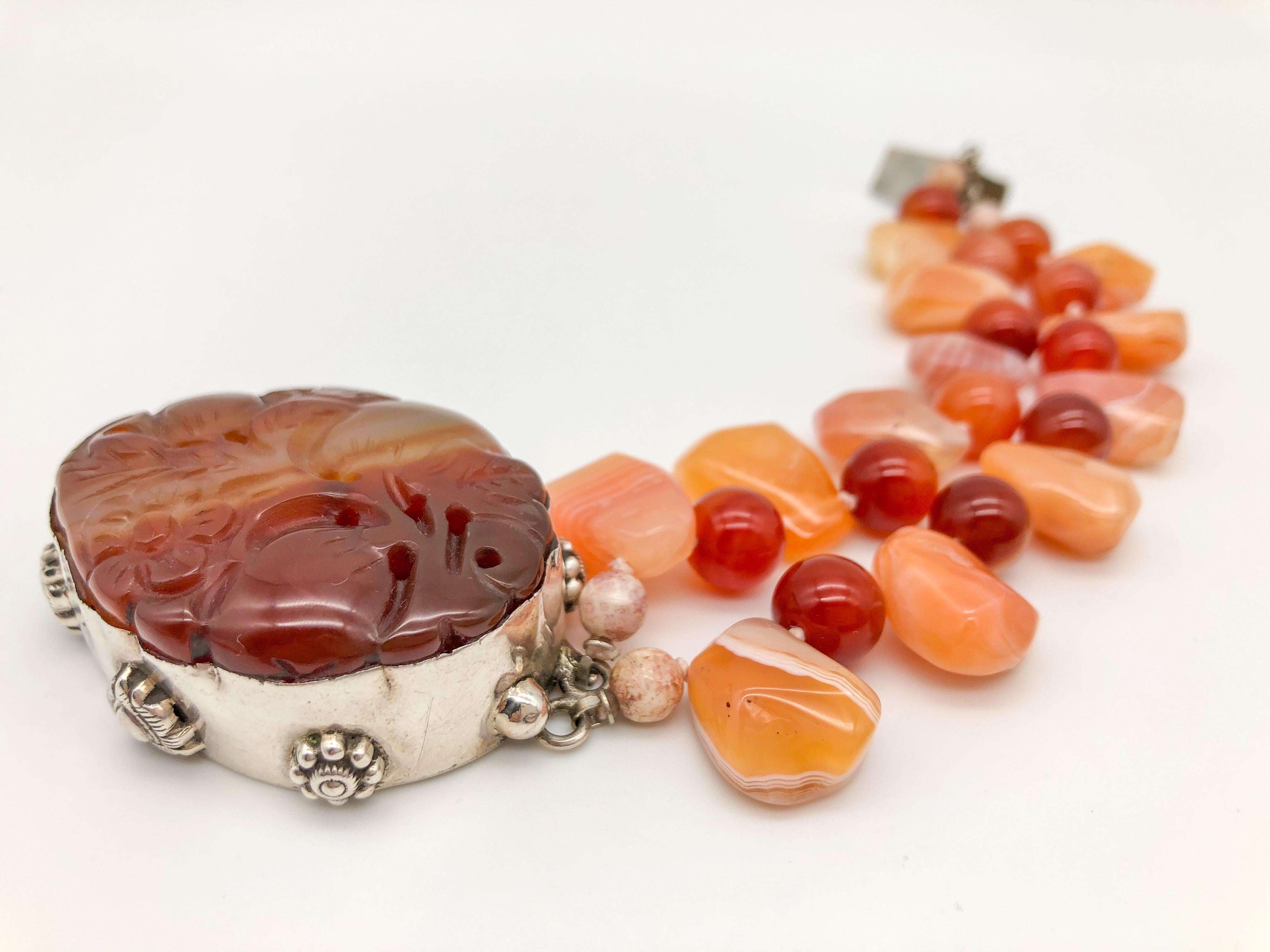 One-of-a-Kind
Carved Carnelian clasp anchor a 2-strand bracelet.
Two strands of mixed carnelian bead beads both translucent and opaque encircle a large carnelian carving of a peach tree in bloom. The carnelian carving is mounted on a sterling