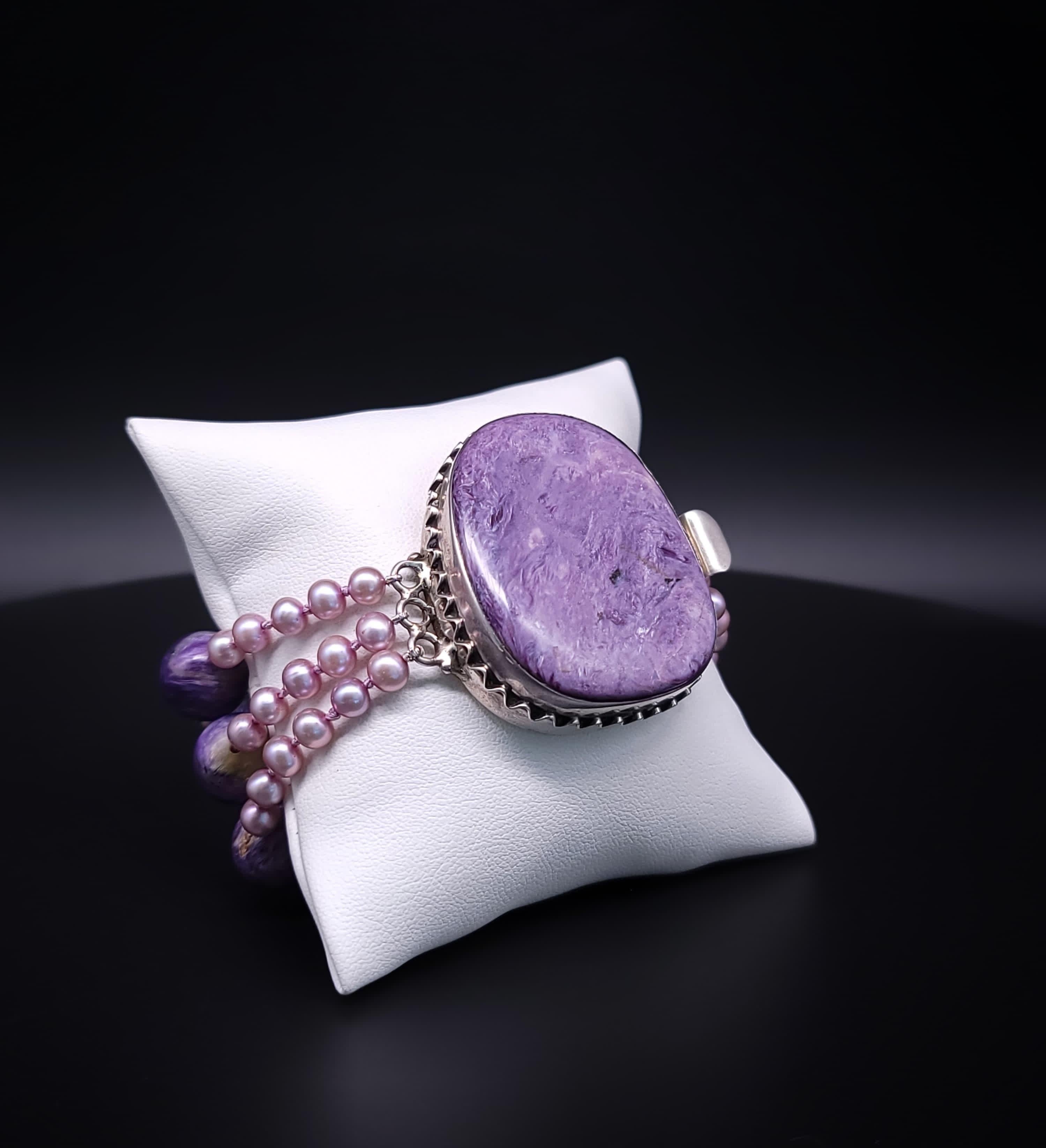 Un bracciale davvero unico e irripetibile, caratterizzato da una splendida combinazione di gemme Charoite viola e perle d'acqua dolce rosa. La caratteristica principale del bracciale è la sua sorprendente chiusura, che funge da centrotavola,