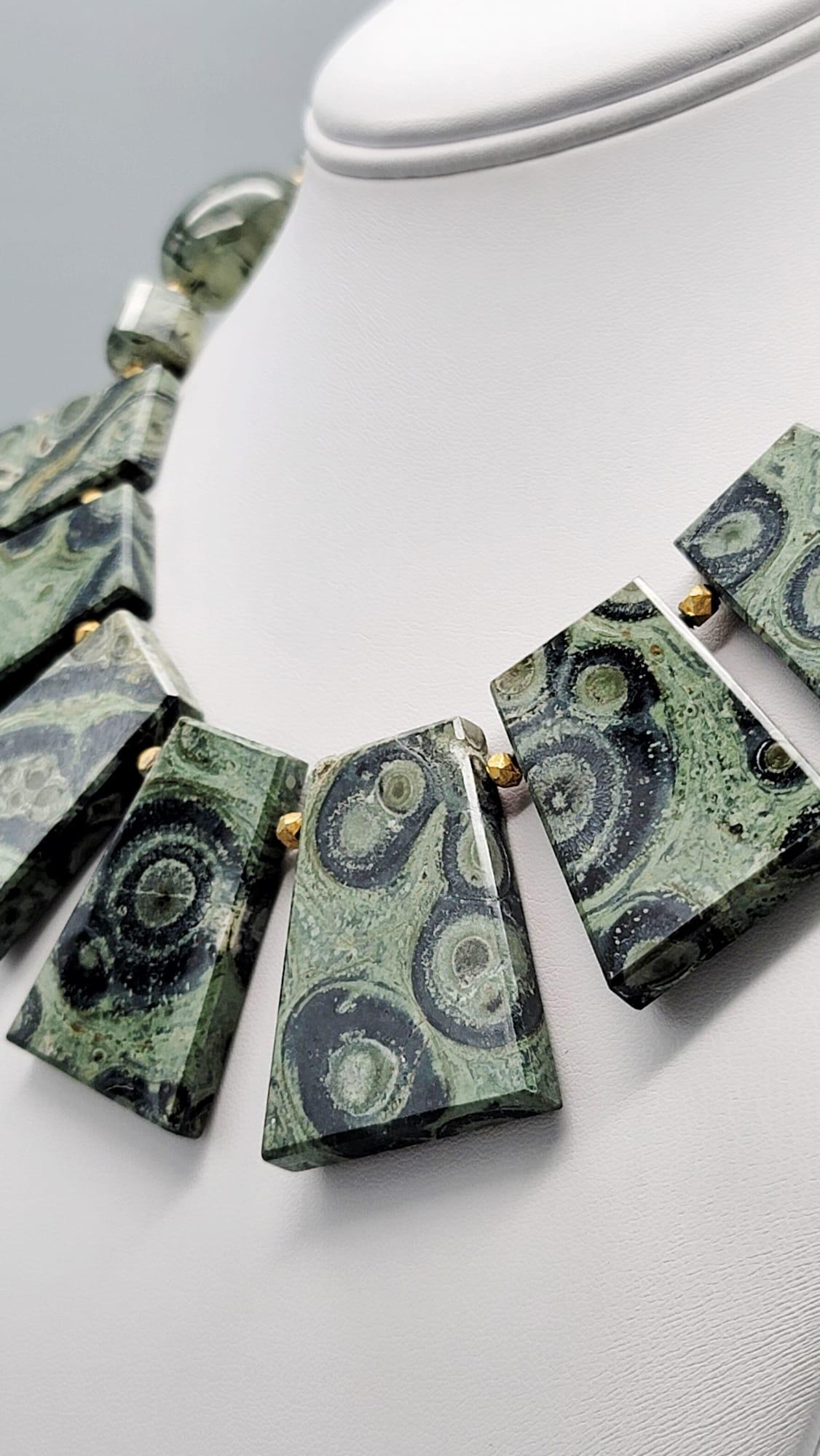 One-of-a-Kind

Kambaba jasper is one of the oldest materials in our stone lexicon. This interesting green and black stone cut into a rhomboid shape permit the dramatic collar to lie flat. the polished translucent rutilated green Quartz translucent