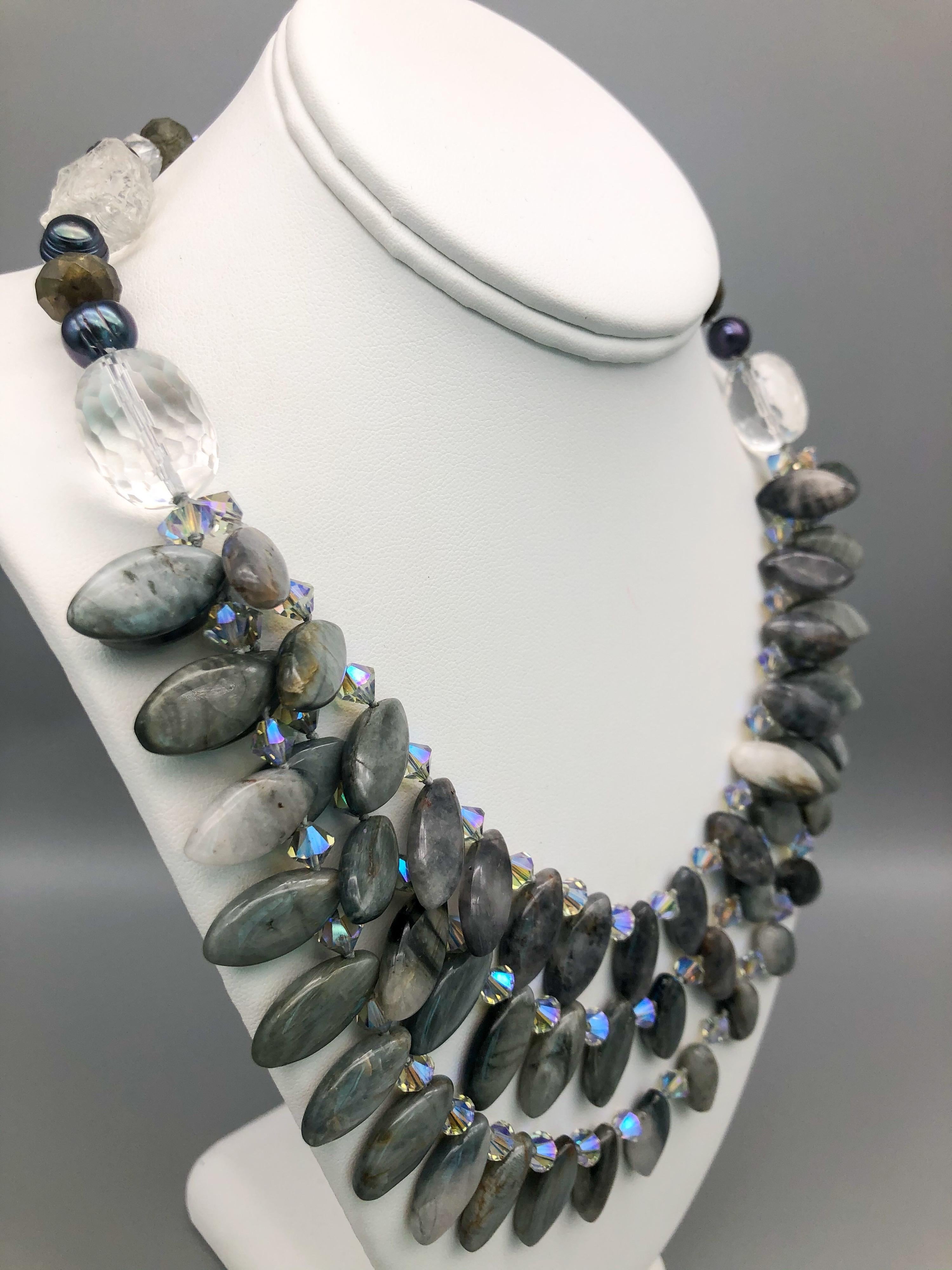 One-of-a-Kind
Highly polished Labradorite petals spaced between Swarovski Crystals are draped into 3 strands caught at the collarbone with a large cut Crystal bead to form a single strand continuation of hammered Crystal gray Pearls and faceted