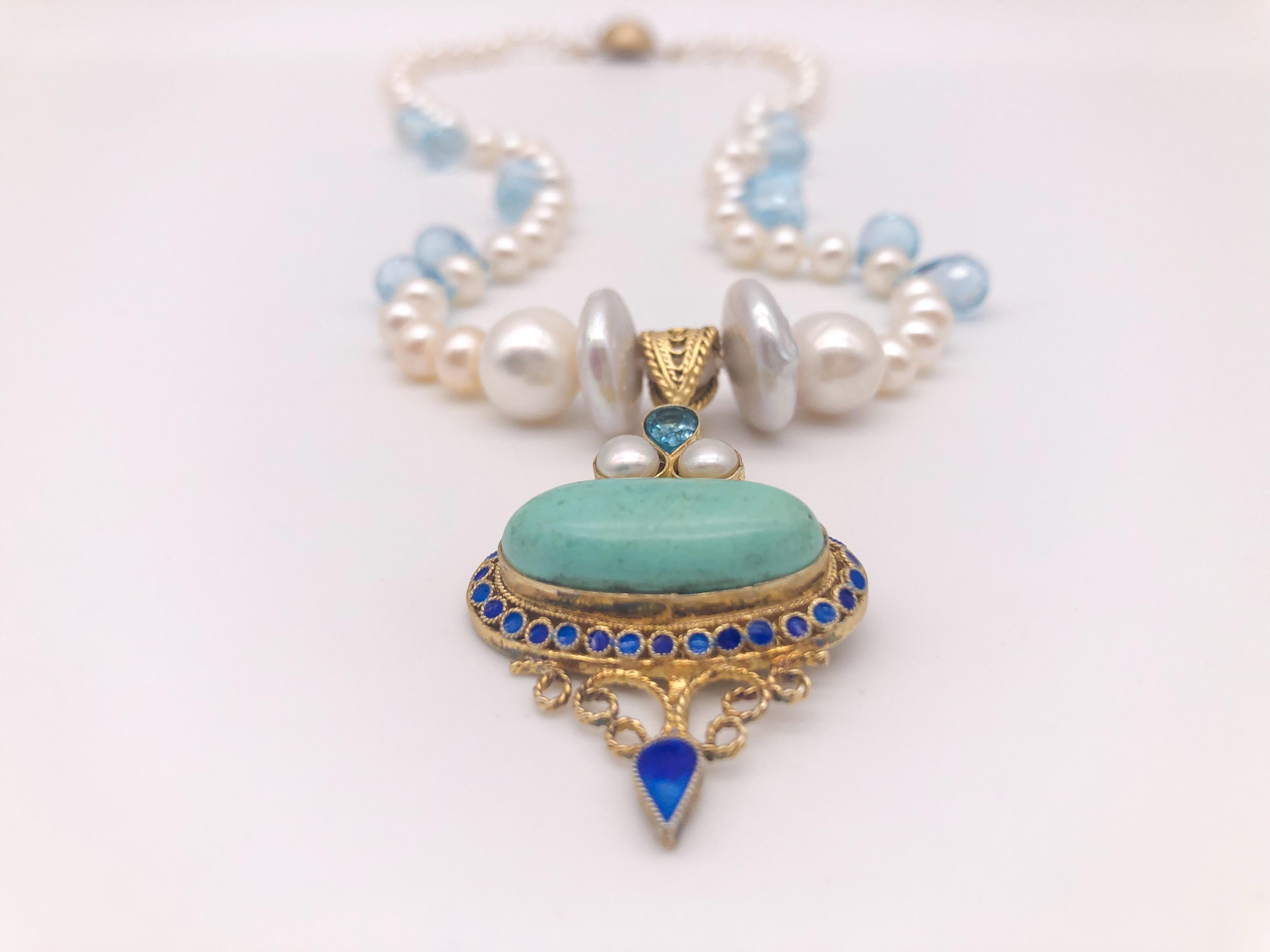 Unique en son genre
Collier d'un seul rang de perles de 6 mm nouées à la main entre des gouttes de topaze bleue.
Le collier supporte un pendentif Barbara Garwood en topaze bleue, perle et turquoise émaillée. Le pendentif a été fabriqué en Mongolie