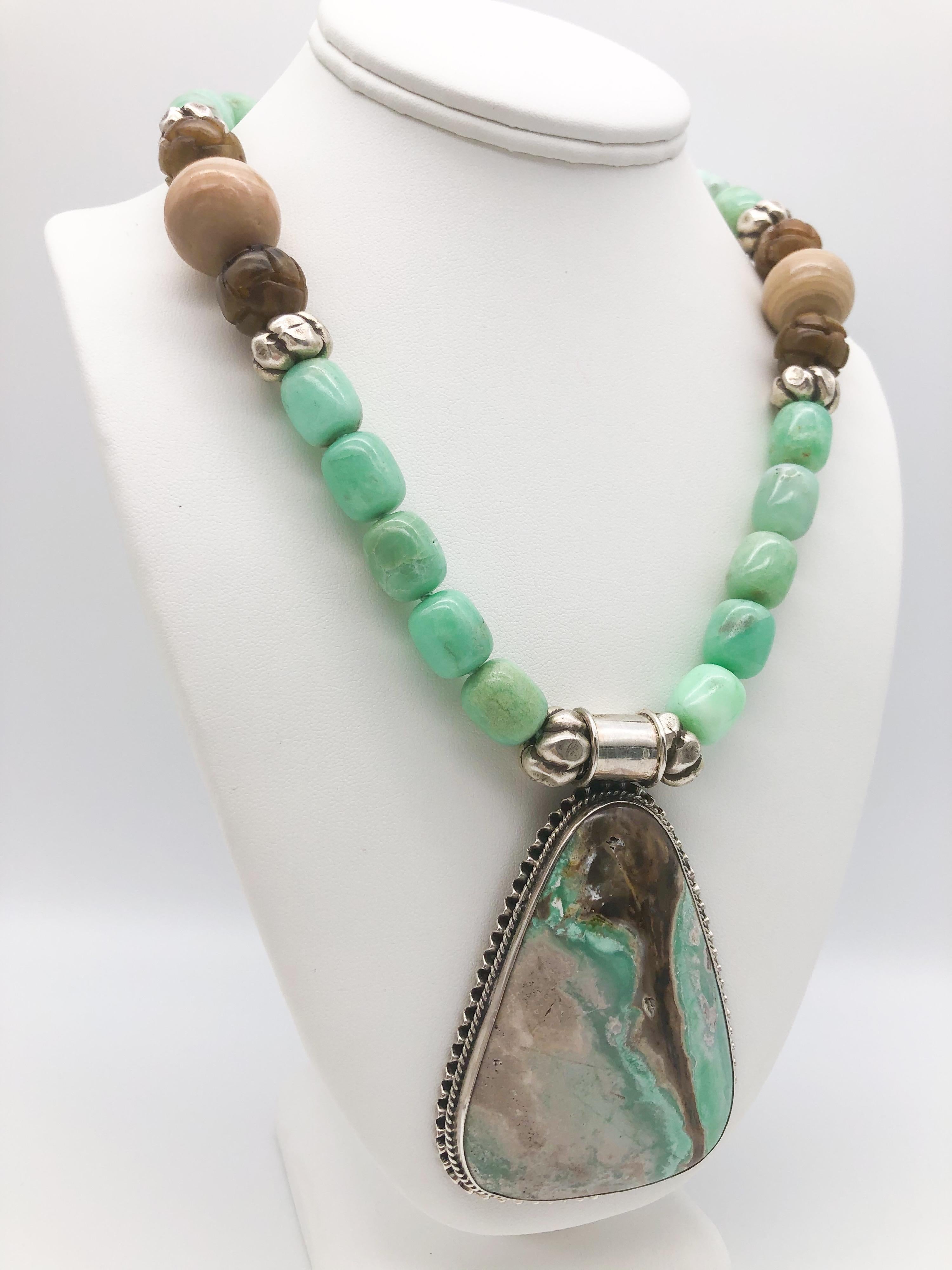 One-of-a-Kind

A polished Chrysoprase Specimen set in Sterling Silver makes a one-of-a-kind Pendant. 
The surrounding necklace picks up the colors of the stone. Soft green polished Chrysoprase, carved dark brown Tobacco Jade, creamy 24mm Jasper