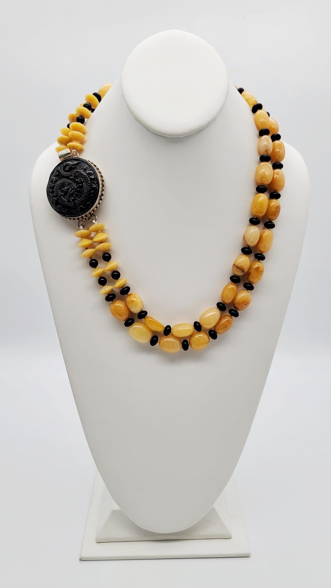 One-of-a-Kind

Richly colored Honey Jade and black Onyx pair in this striking matinee length double strand necklace. Meant to be worn as a side clasp a large  (2”x2”) carved Chinese onyx dragon is set into a silver frame holding the necklace