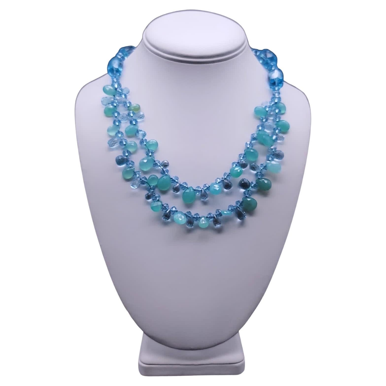 One-of-a-Kind

A blue topaz necklace with 2 strands to the collar bone and a single strand under the collar. The rich blue topaz, cut, faceted, and tear-dropped is accented by a green-blue chalcedony blending softly with the blue topaz. The clasp is