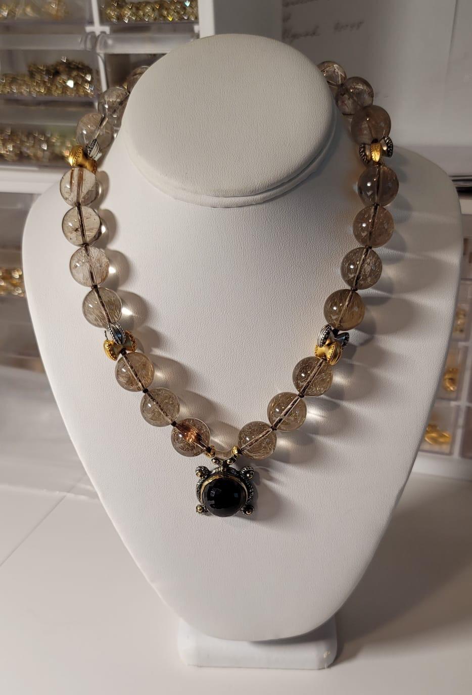 One-of-a-Kind

18m.m carefully matched rutilated quartz polished beads strung between sterling silver and vermeil bow knots suspends an elegant Bora handcrafted silver and brass faceted pendant holds a brilliant faceted large smoky quartz stone.
The