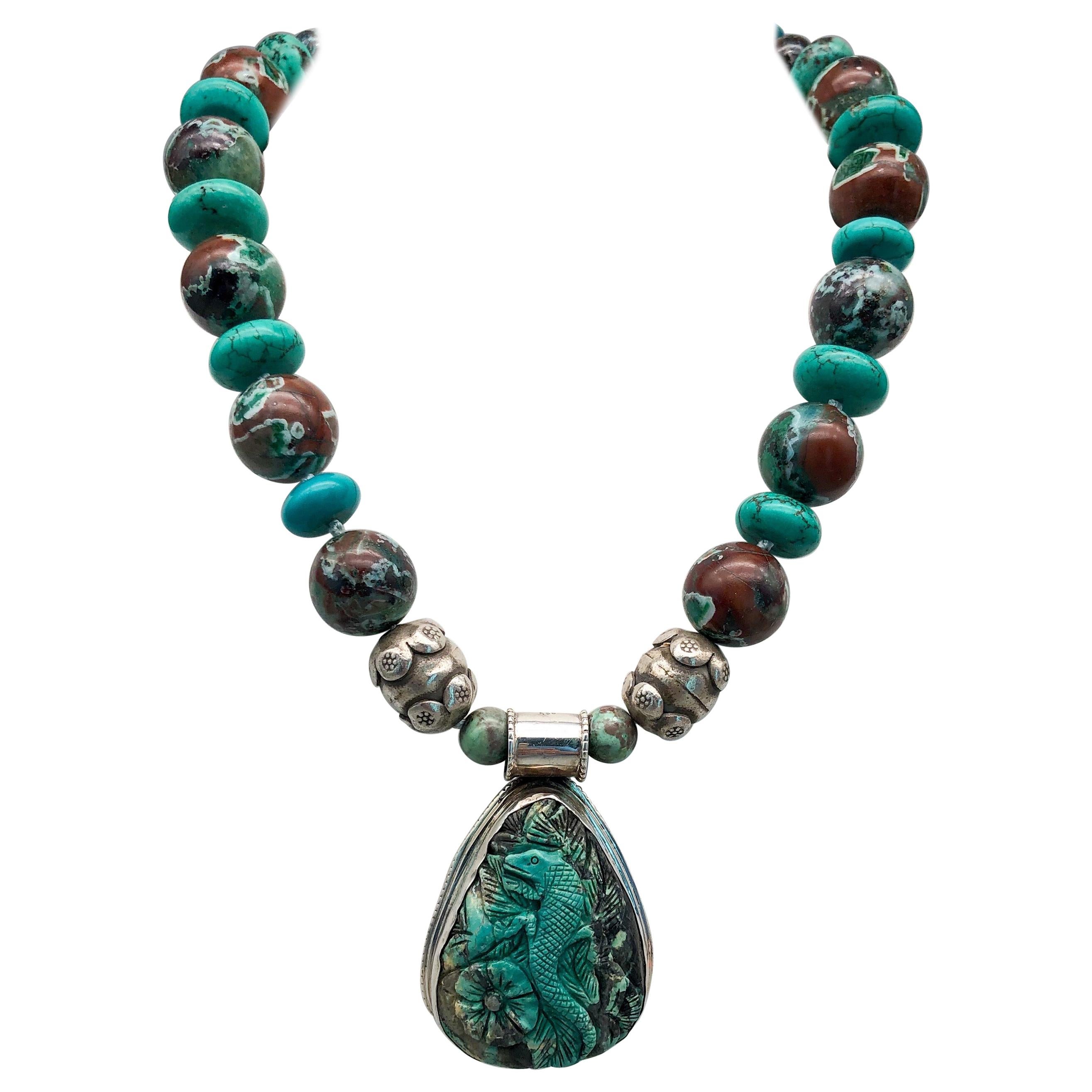 One-of-a-Kind

This interesting pendant of a lizard resting on a flower carved in China is just the beginning of this arresting combination of stones 18mm Lively patterned polished  Chrysocolla with an unusual amount of rich brown matrix alternates
