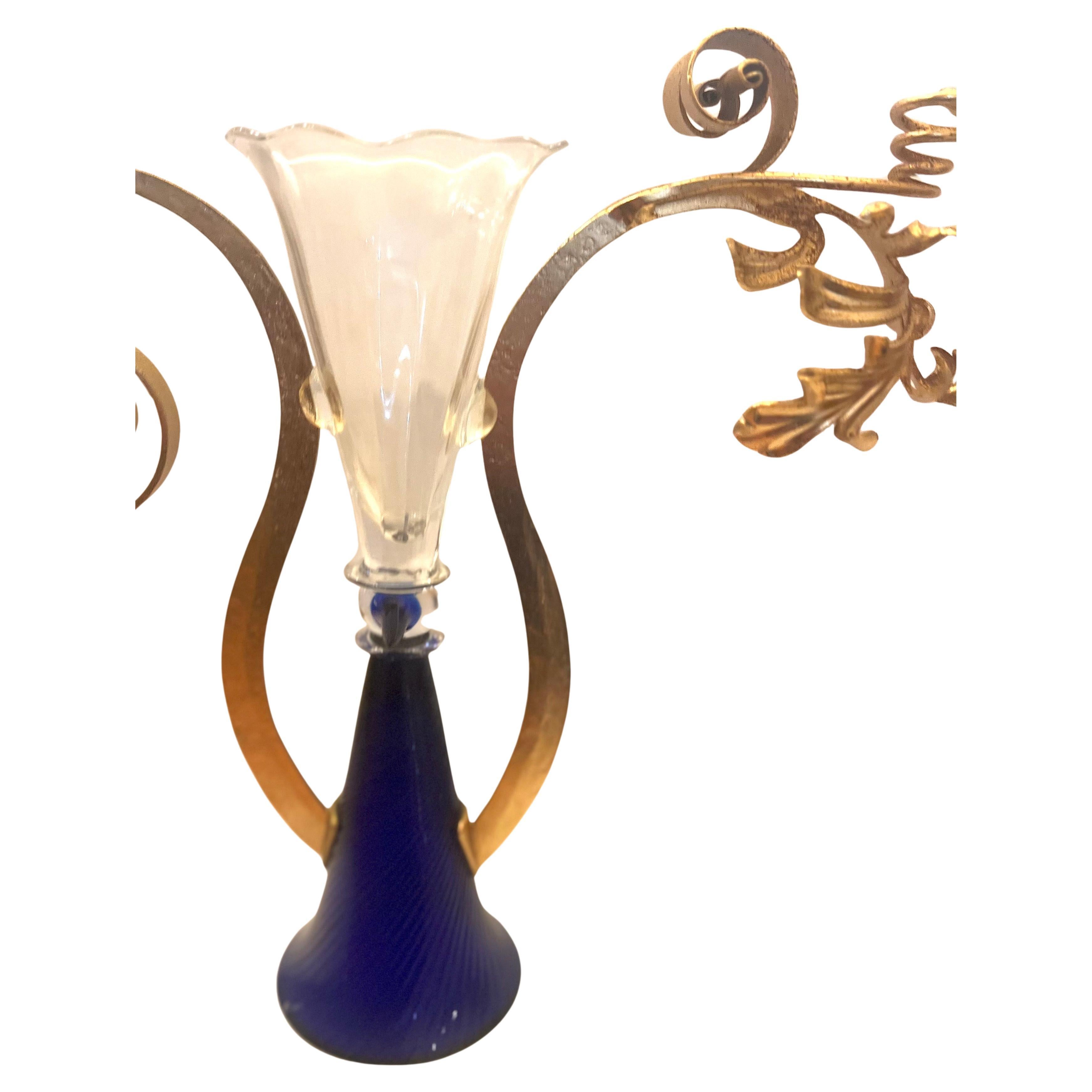 
Vetri incolori e trasparenti al cobalto senza piombo, oro metallico; soffiati con applicazioni a caldo, metallo forgiato e dorato a mano, incollati. Alto vaso soffiato composto da due forme coniche uguali, con bordi leggermente svasati posizionati