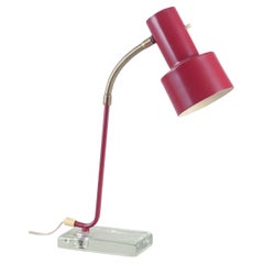 AJH, Svezia. Lampada da tavolo industriale in metallo laccato rosso su base di vetro.