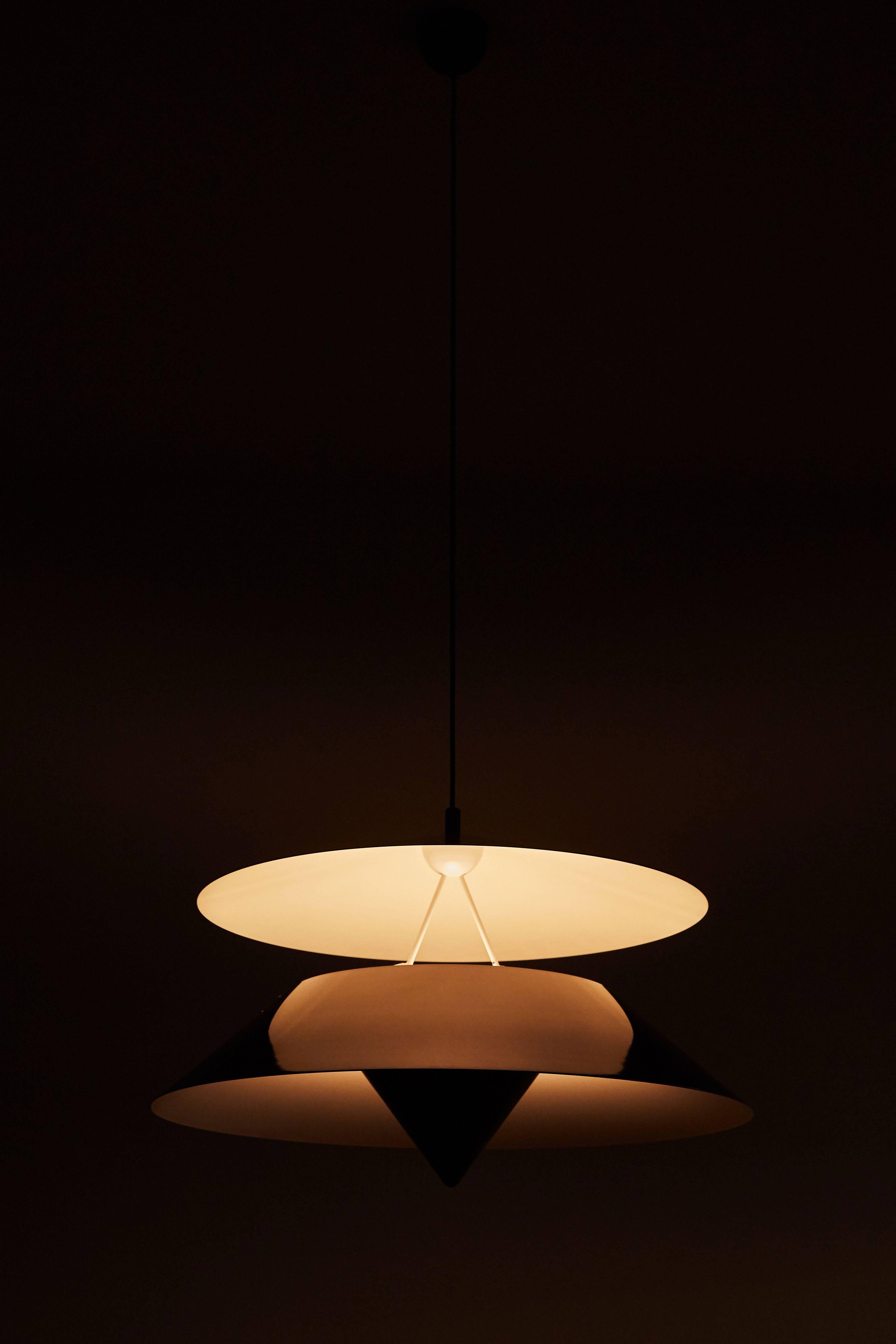 Akaari pendant by Vico Magistretti designed in Italy for Oluce, 1985. Painted aluminum and metal. Provides uplight and downlight. Original canopy. Wired for US junction boxes. Takes two E27 75w maximum bulbs.