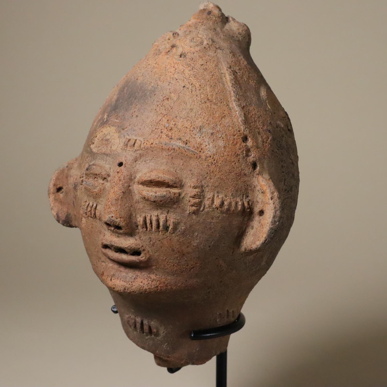 Store closing March 31. This is an earthenware or terracotta portrait from the Akan people of Ghana. 19th century or earlier. 
This one has a lively, animated expression. There are raised scarification marks on the cheeks, temples, and on the brow.