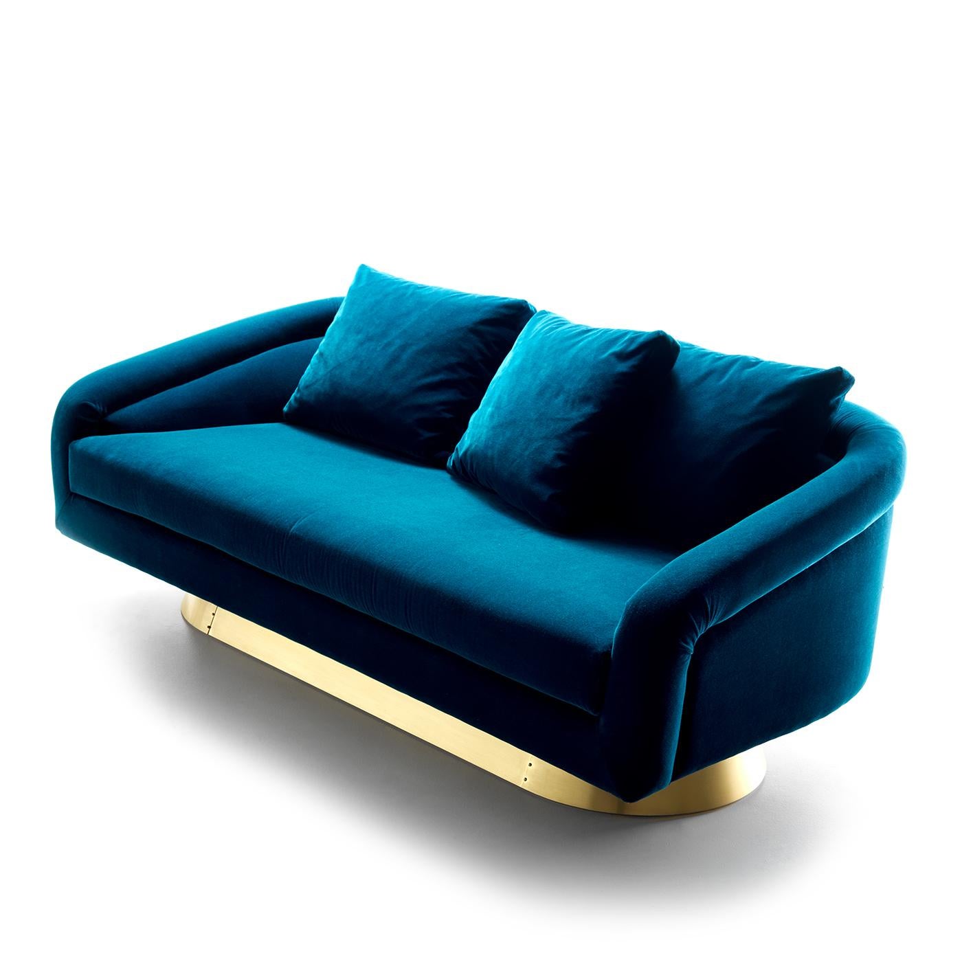 Inspired by the decadent aesthetic of the Art Deco, this stunning sofa will bring a dramatic look to a mid-century, modern living room. The unique silhouette is raised on an elongated oval brass plinth whose warm shimmer elegantly coordinates with