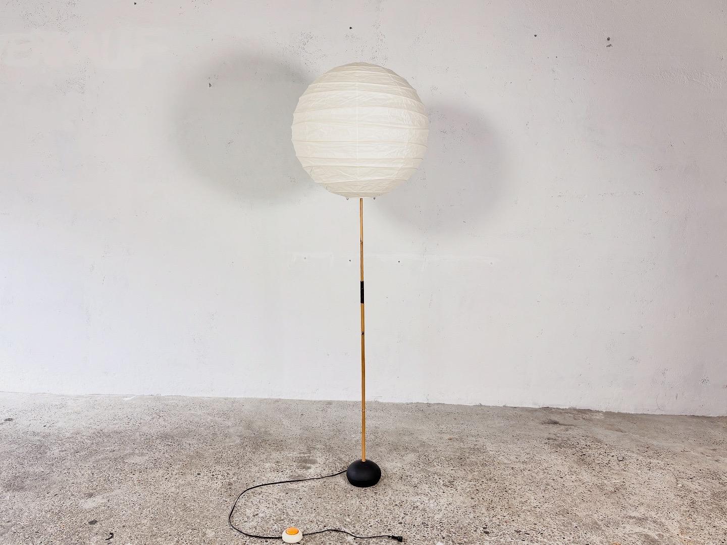 BB3 floor lamp with Washi Paper lampshade designed by Isamu Noguchi.

Manufactured by Ozeki, Japan.

This floor lamp features a white Washi paper lampshade, a bamboo shaft and a spherical  iron base. The shade is marked with a red sun and crescent
