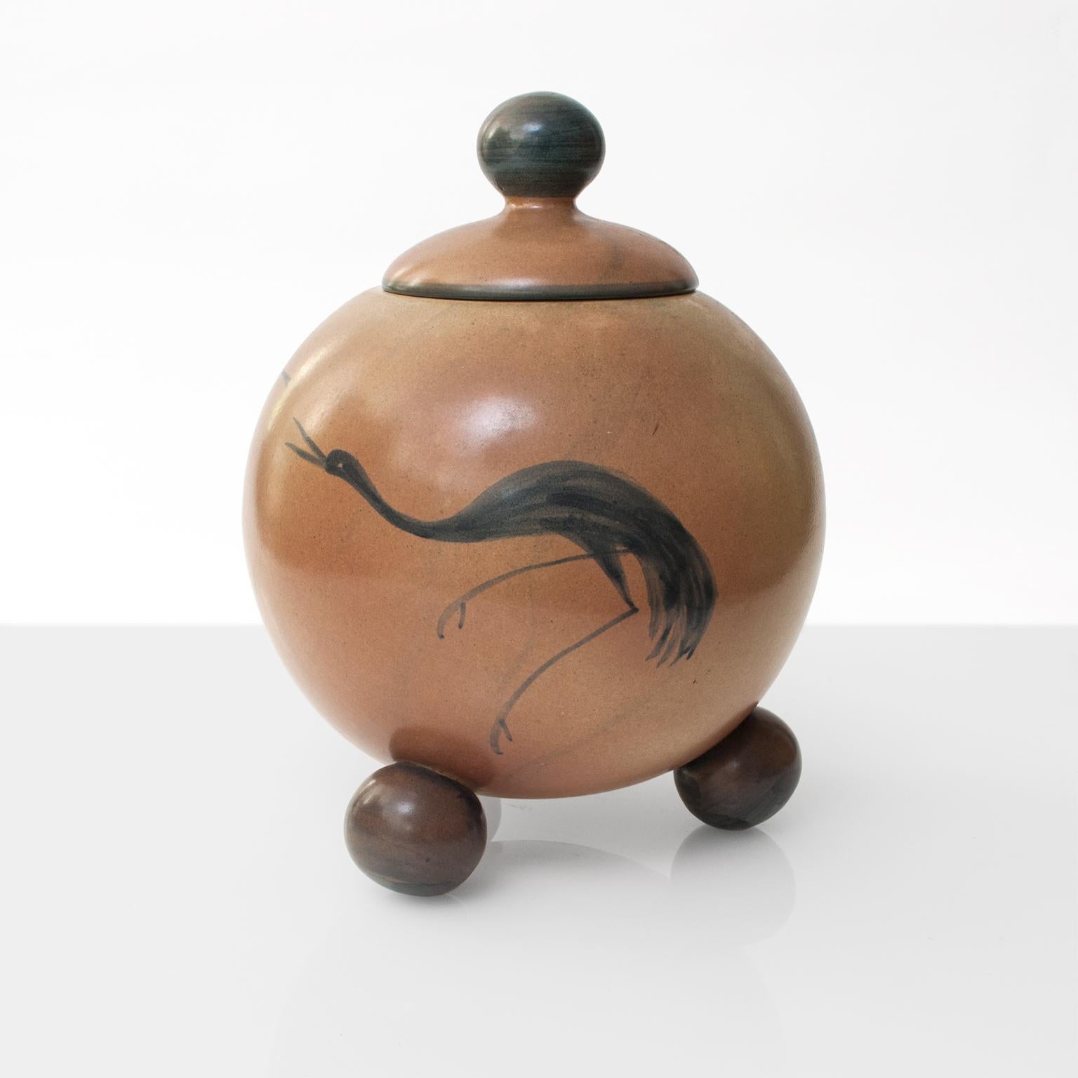 Åke Holm for Höganäs, Swedish Art Deco ceramic jar with lid hand decorated with a winged female figure, a crane and flora. The jar sits on 3 ball feet and the lid has a ball shaped knob. Holm's works are included in the Höganäs museum's permanent