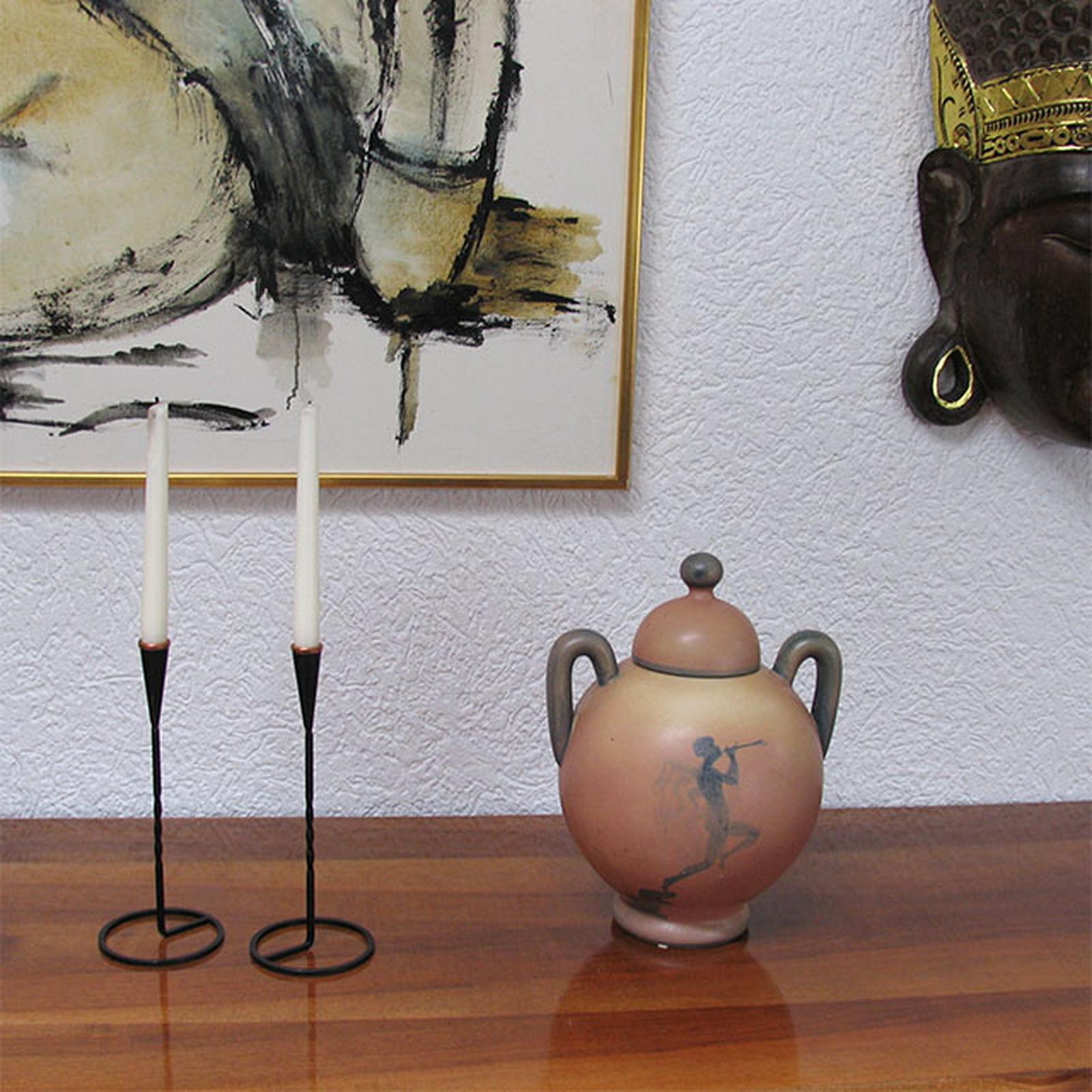 Schwedische Keramikurne im Art-Deco-Stil mit Deckel von Åke Holm für Höganäs.
Vorderseite mit einer geflügelten Figur, die eine Trompete spielt, die andere Seite mit einer Blume verziert. Der Deckel hat einen kugelförmigen Knauf. 
In sehr gutem