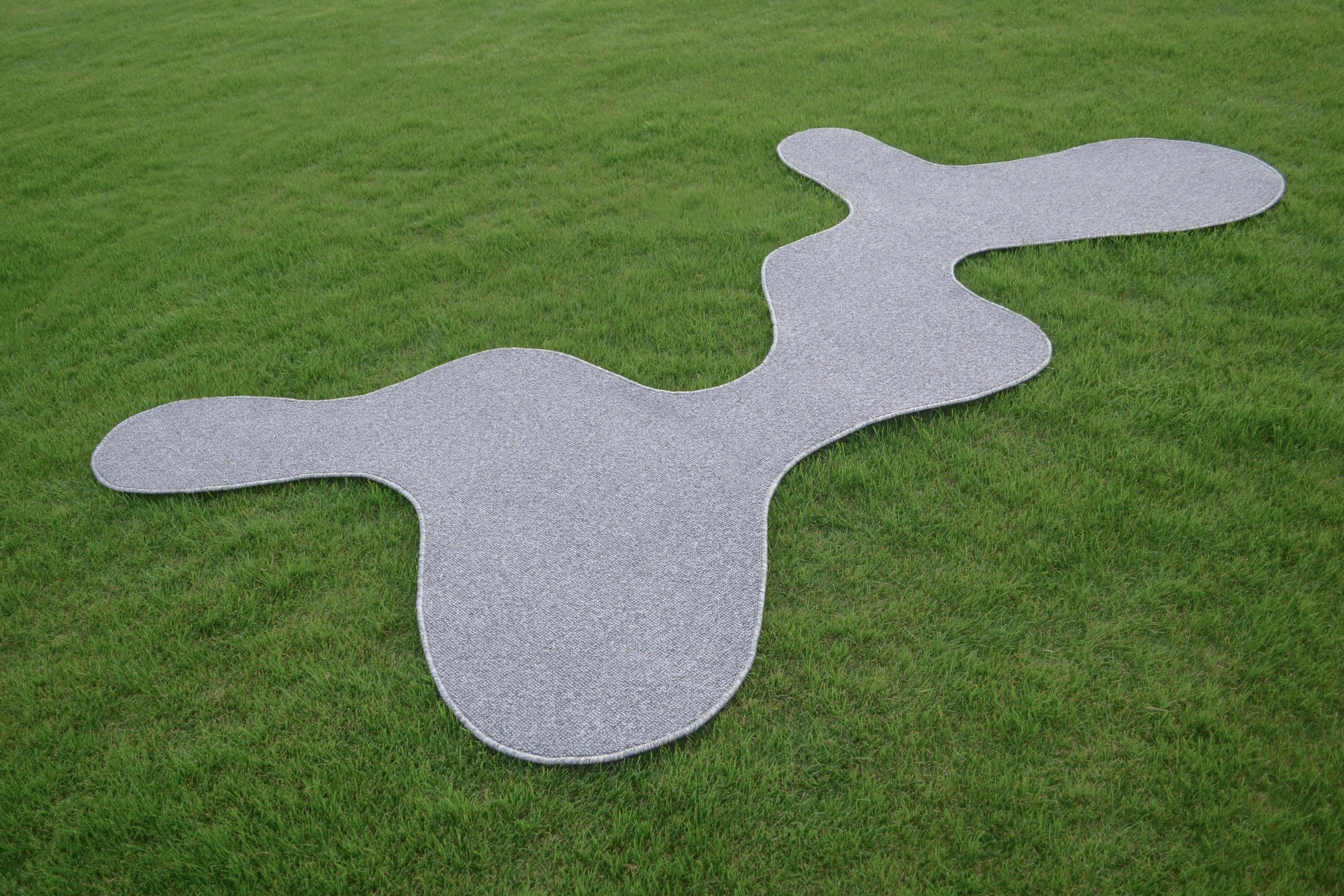 AKI rug B ist ein organisch geformter Teppich, der in Kombination mit den Elementen, die ihn umgeben, verschiedene Formen bildet, wie eine negative Raumzeichnung auf dem Boden.

Mit dem Ziel, das Unerwartete des Organischen zu umarmen, sind die