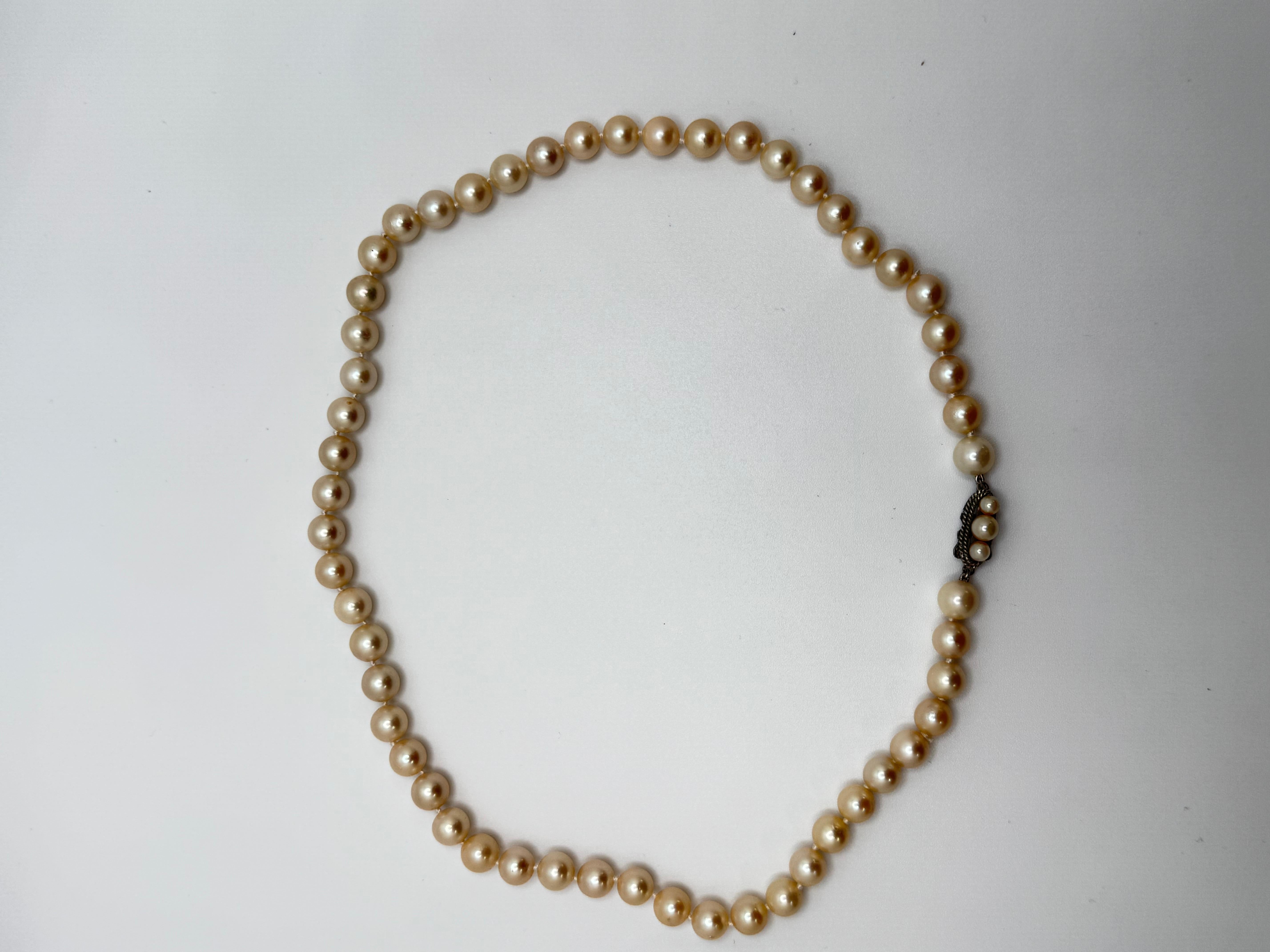 This classic Akoya cream pearl necklace measures 18 inches in length and exudes timeless elegance. It features a silver clasp measuring approximately 14.5mm by 6.5mm, adding a sleek touch to the overall design. The clasp is adorned with three small