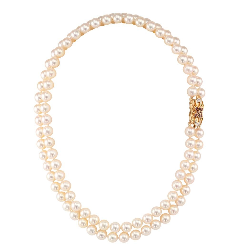 Akoya cultured pearl double strand necklace with ruby and diamond gold clasp. Featuring a pair of nested strands of cultured pearls measuring 7 ½ - 8 mm, completed by a ruby and diamond 14-karat yellow gold clasp. We love the lush and thick nacre