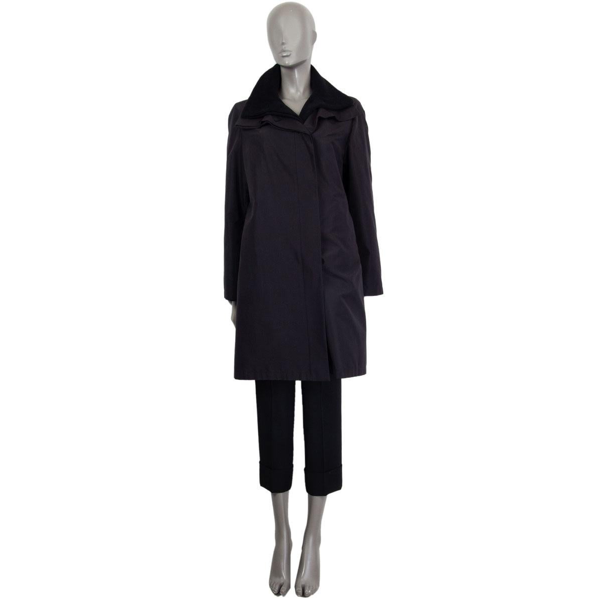 100% authentic Akris double layer coat in black silk (100%) with a stand collar. Closes on the front with buttons. Partially lined in viscose (100%). Inner layer coat is in black angora (50%) and wool (50%) with a stand collar and slit pockets.