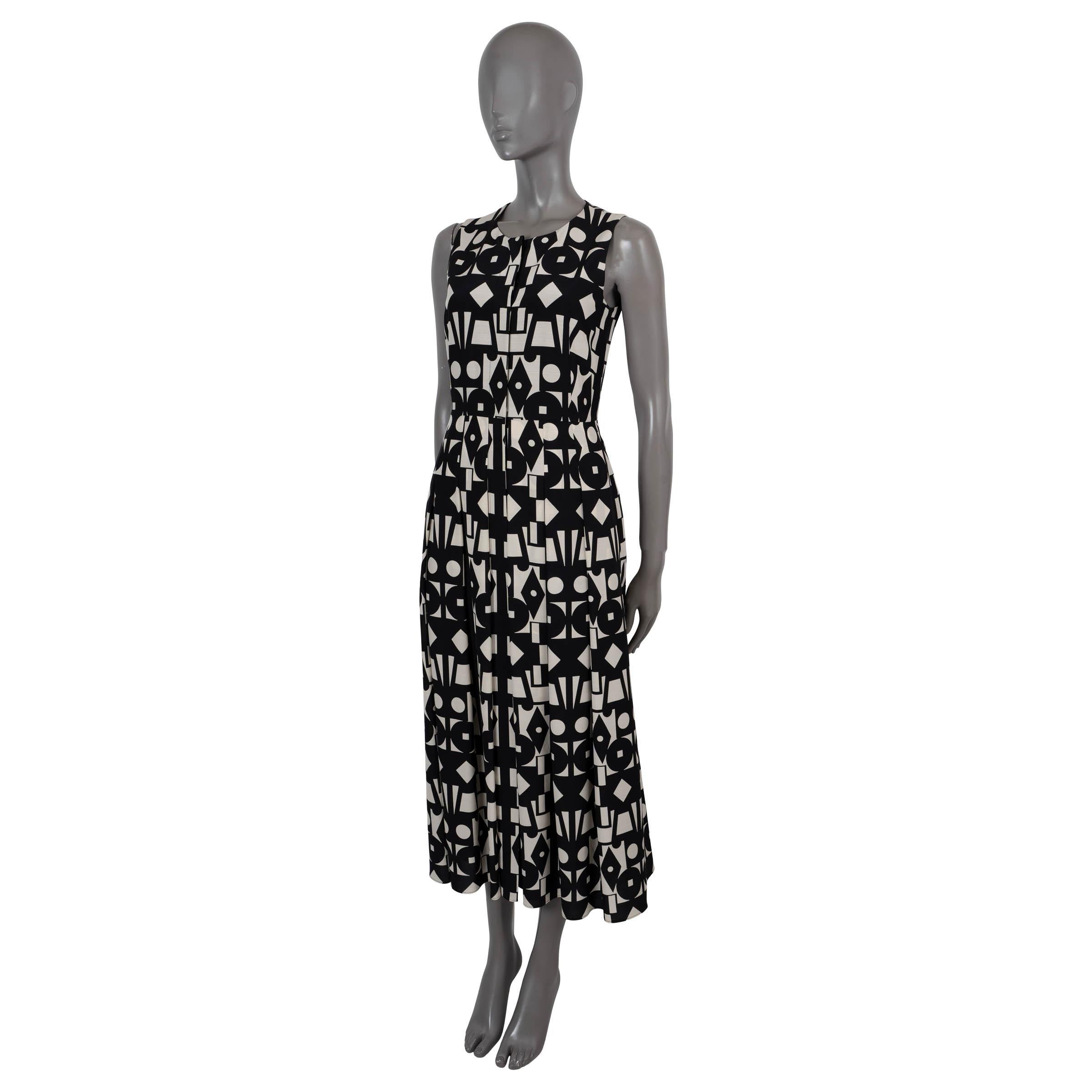 100% autentico abito senza maniche di Akris in voile stampato geometrico bianco e nero in lana (53%) e seta (47%). Presenta un top sartoriale con scollo rotondo, una gonna a pieghe e tasche laterali in vita. Si apre con bottoni nascosti sul davanti
