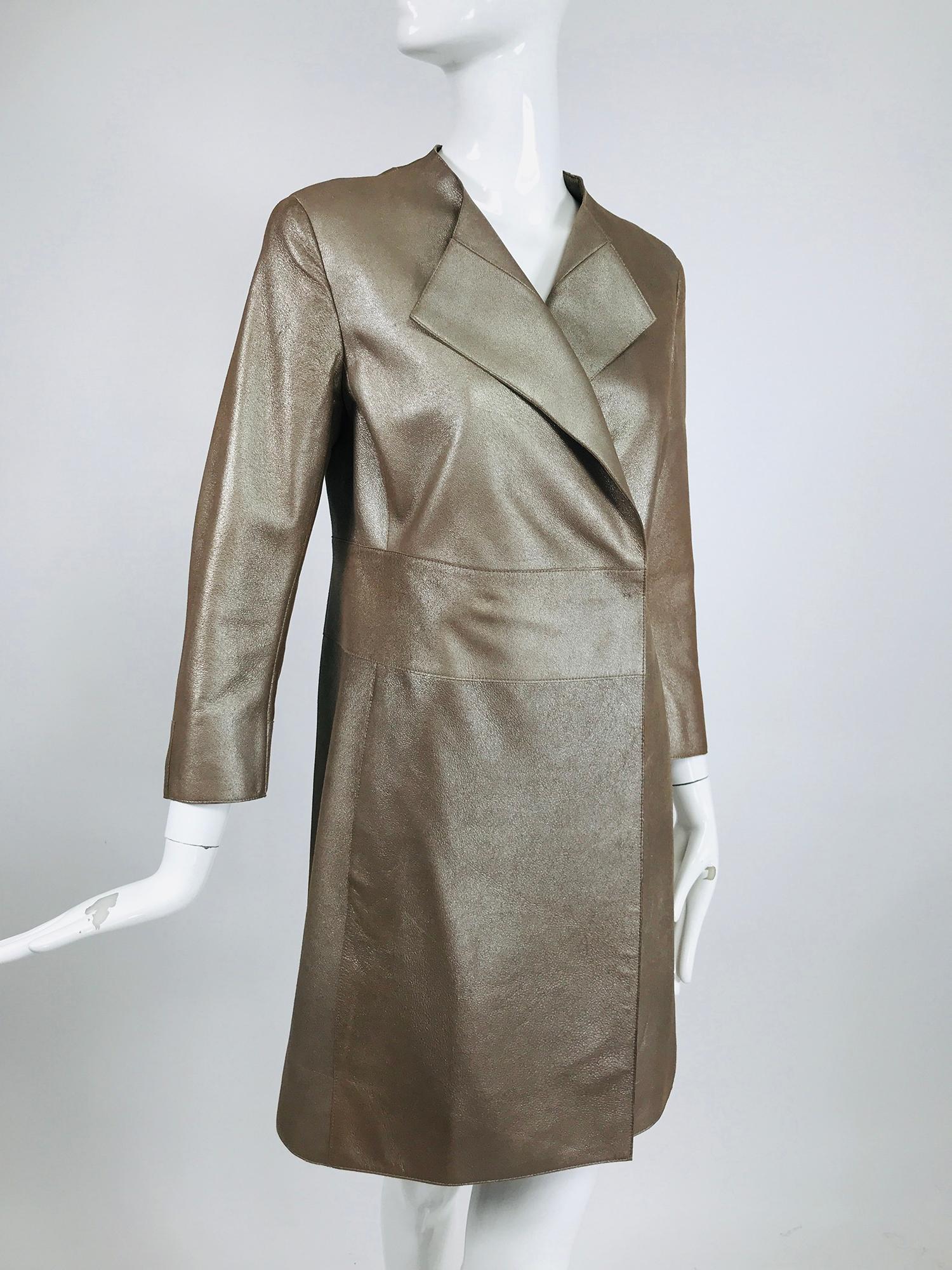 Akris bronze gold lamb suede coat. Collarless coat with wing lapels, wide band at waist with two hidden snaps to close. The coat skirt is cut straight to the hem, there are some on seam hip side front pockets. Wrist length sleeves. Off set side hem