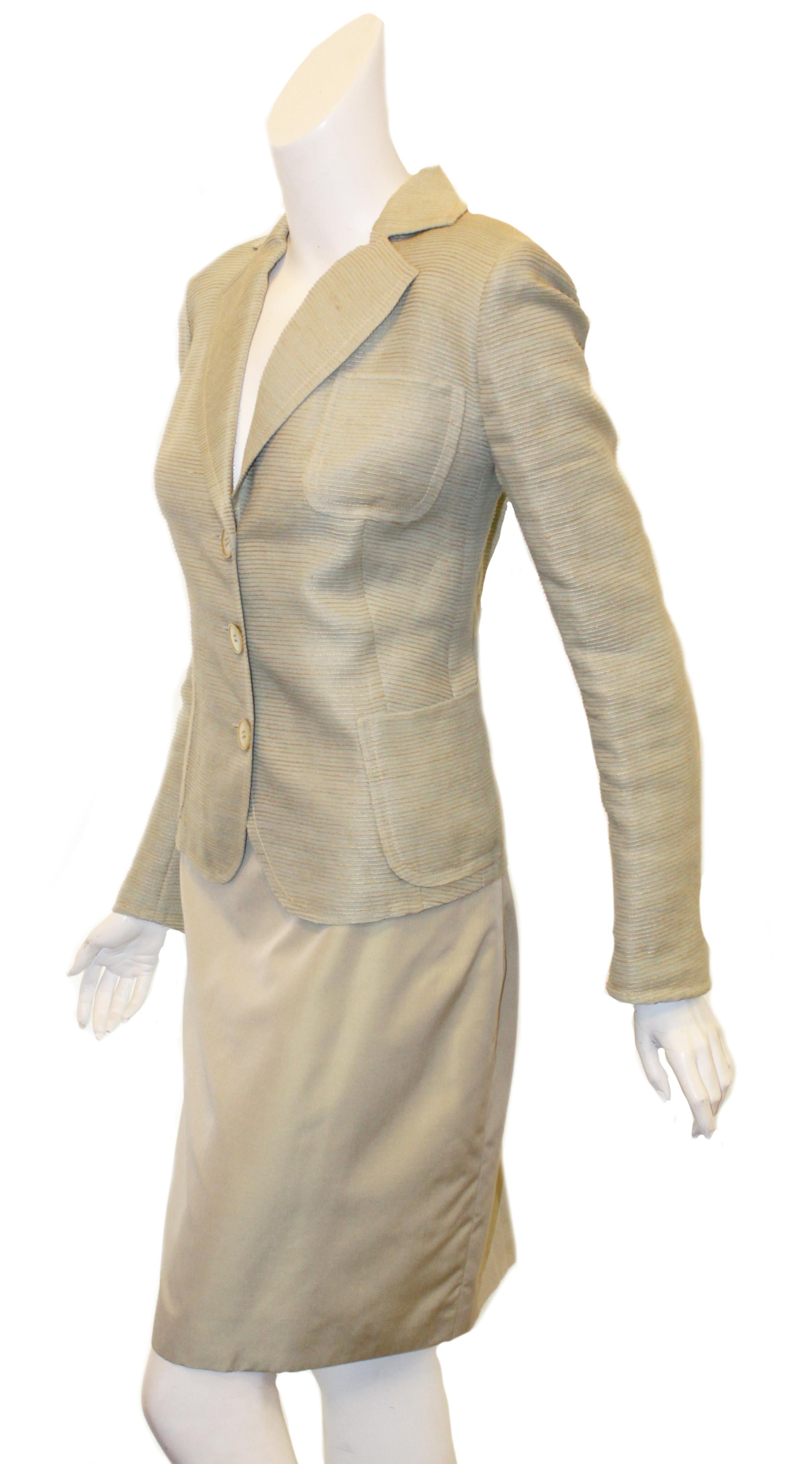 Akris green linen and silk suit features horizontal top stitched design allover jacket. 
3-button, ventless jacket has 3 patch pockets - one at breast and two at hem - and is lined in green silk.  Beige straight skirt finishes the look.  Excellent