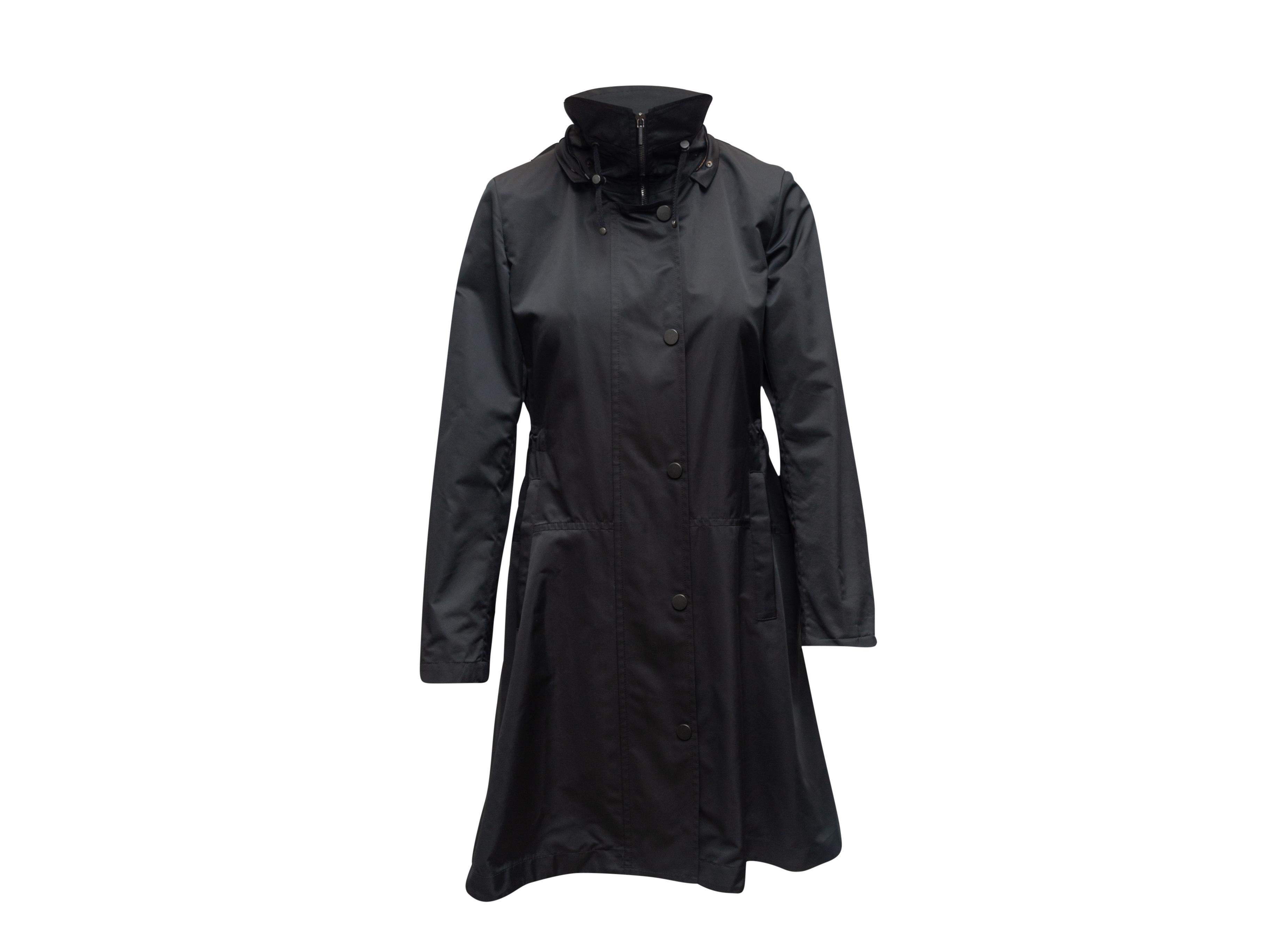 Product details: Black long nylon windbreaker jacket by Akris Punto. Fold collar. Dual hip pockets. Closures at front. 33