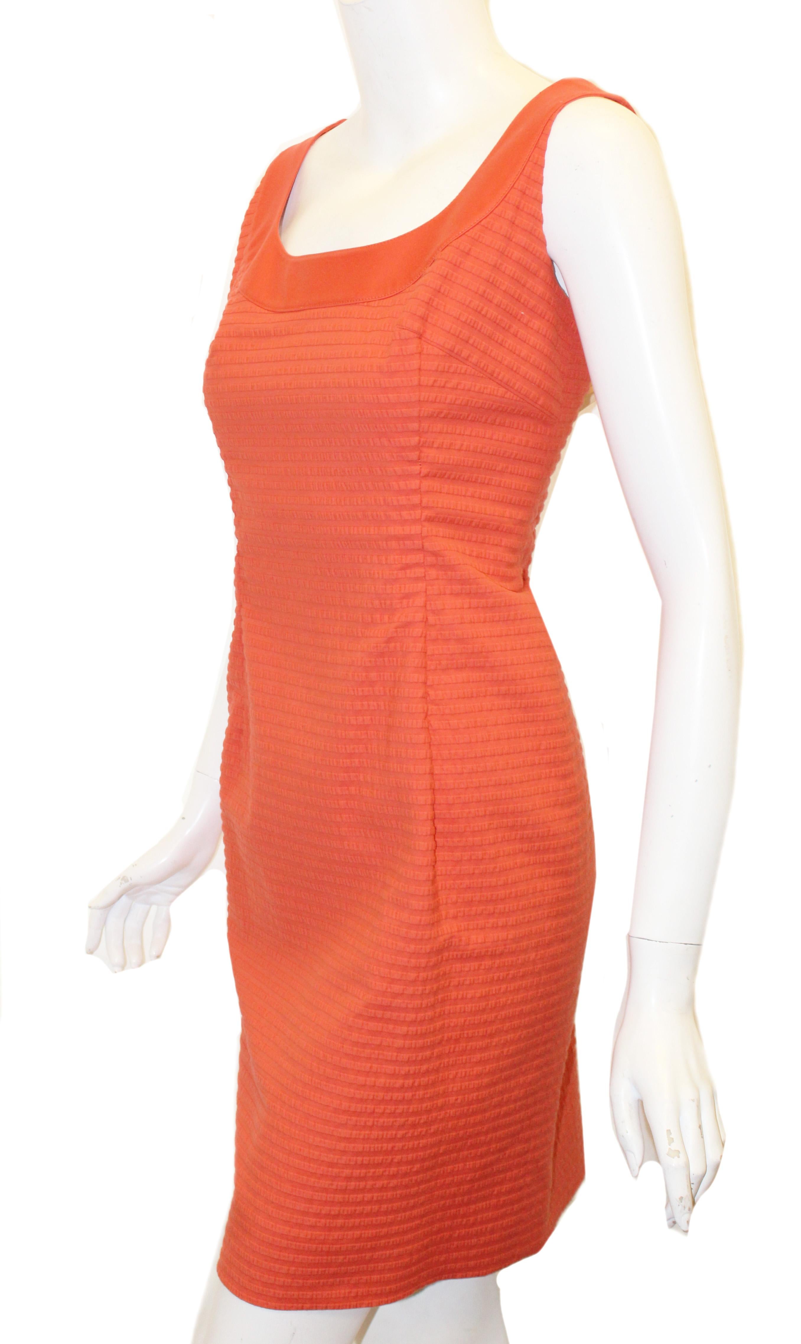 Akris Punto orange puckered fabric dress with round neckline is trimmed with same orange color fabric that is smooth.  This sheath dress contains a hidden zipper at back.  This dress is fully lined and is in excellent condition.  Made in Switzerland