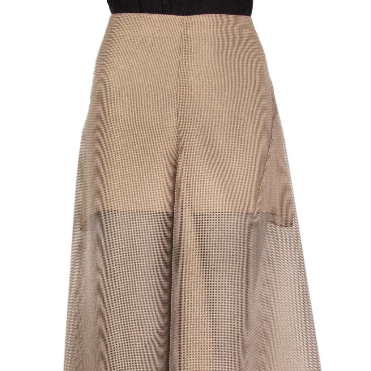 100% authentic Akris sheer flared midi skirt in tan polyester (100%) with net effect. Closes with one button and a concealed zipper on the back and has a sewing-cut at the mid-front and mid-back. Semi-lined in tan viscose (100%). Has been worn and