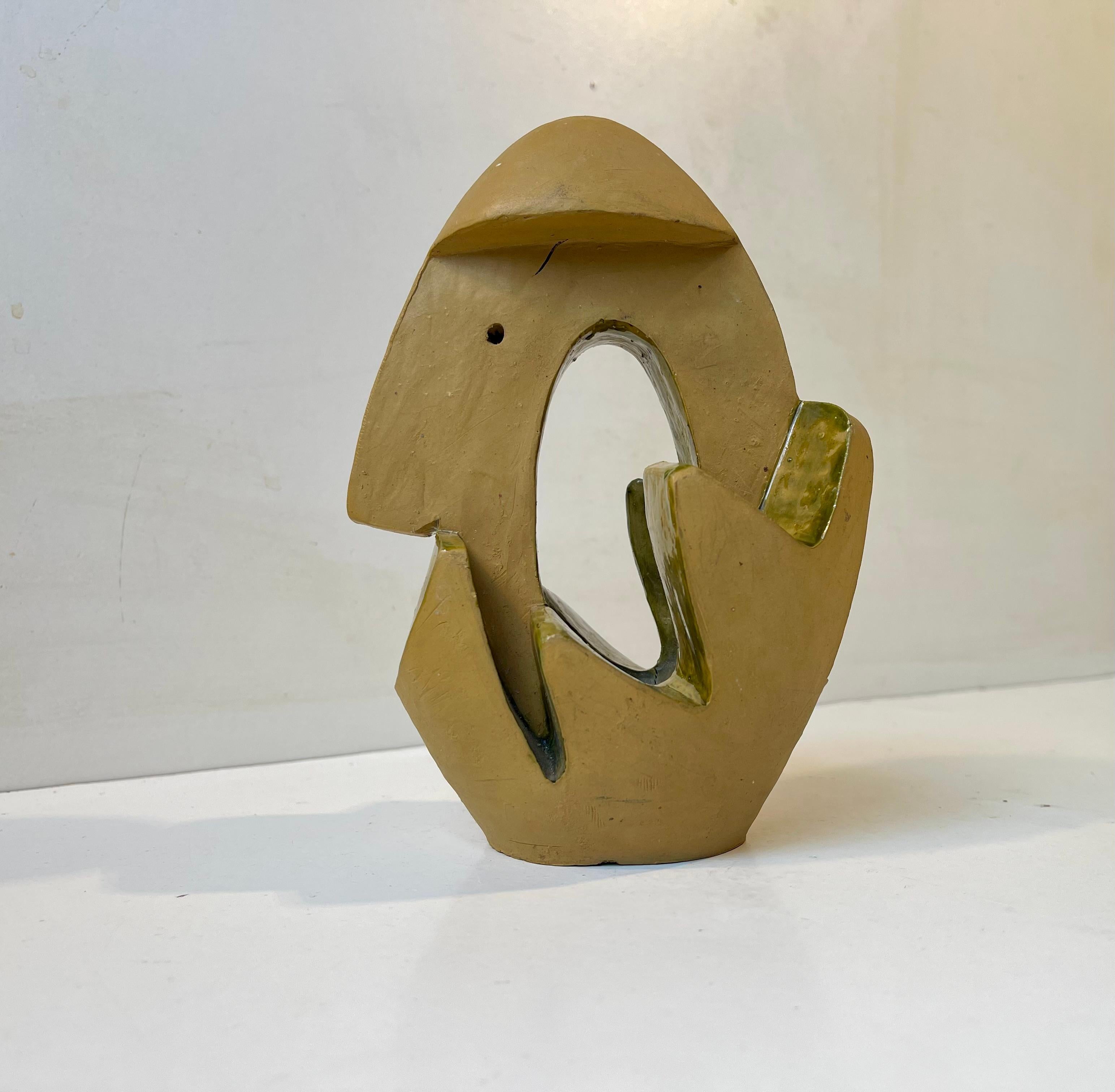 A 1960s sculptural surrealist figurine/ornament in partially glazed and hand-painted ceramic. An abstract form based upon an ovoid main shape. The main color is mustard and the applied glaze olive/pickle in tonality.  Uniquely made by the Danish