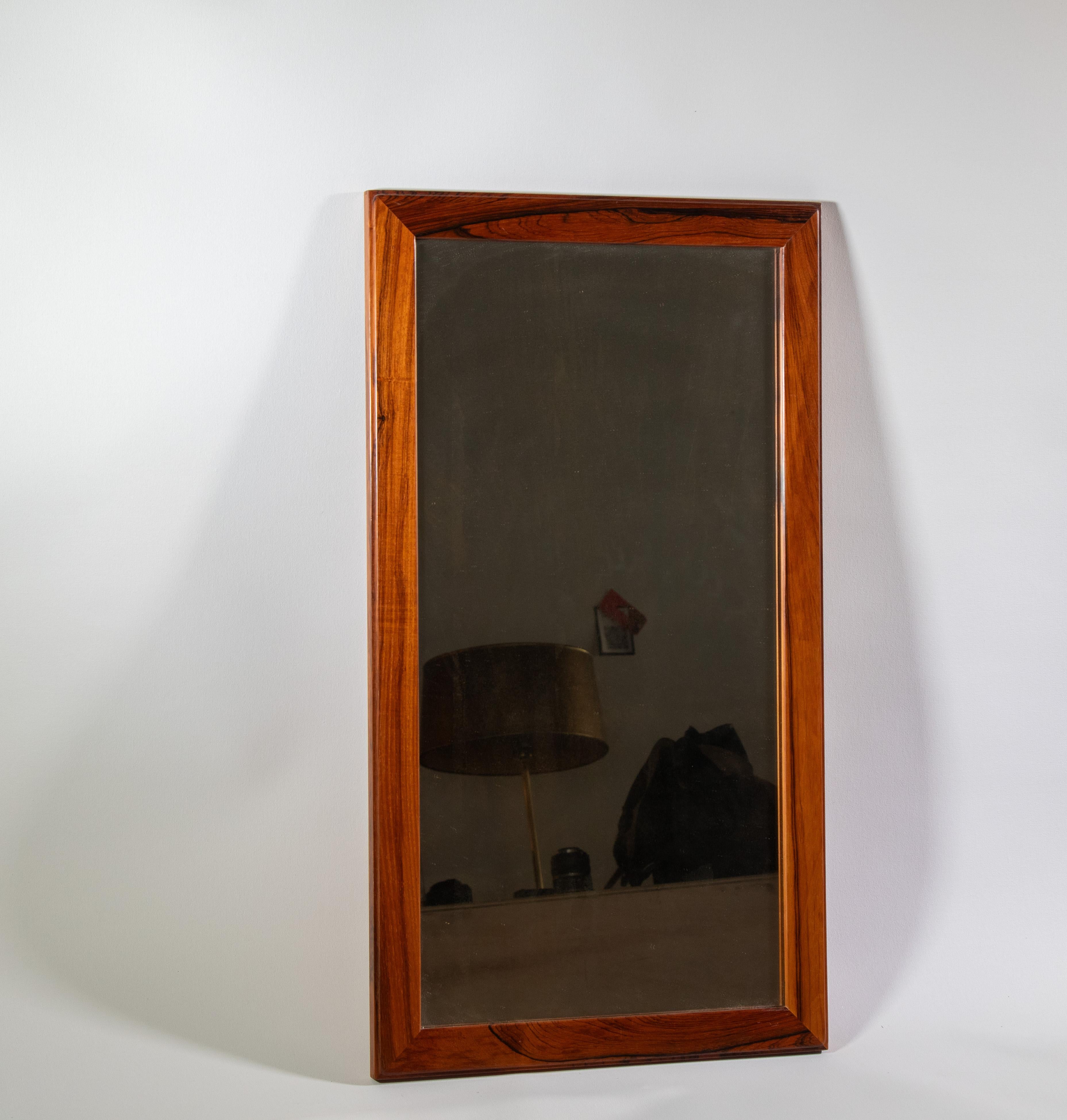 A solid rosewood mirror designed by Aksel Kjersgaard Odder and made in Denmark. A generous size finished in solid rosewood with attractive grain.  The edges feature an inset design, which adds visual interest. A wire is present and allows the mirror