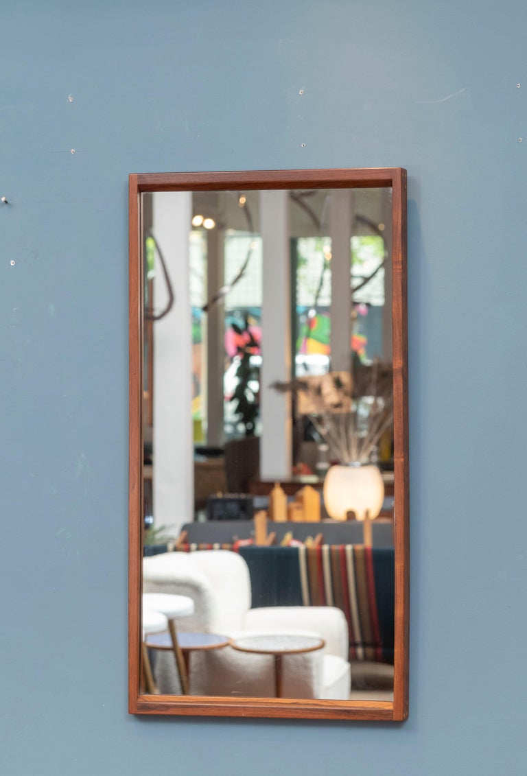 Danish Modern solid rosewood wall mirror designed by Aksel Kjersgaard, Denmark. Sculpted angular rosewood frame showing three joinery dowels at each corner and stamped with manufacturers mark on the rear.