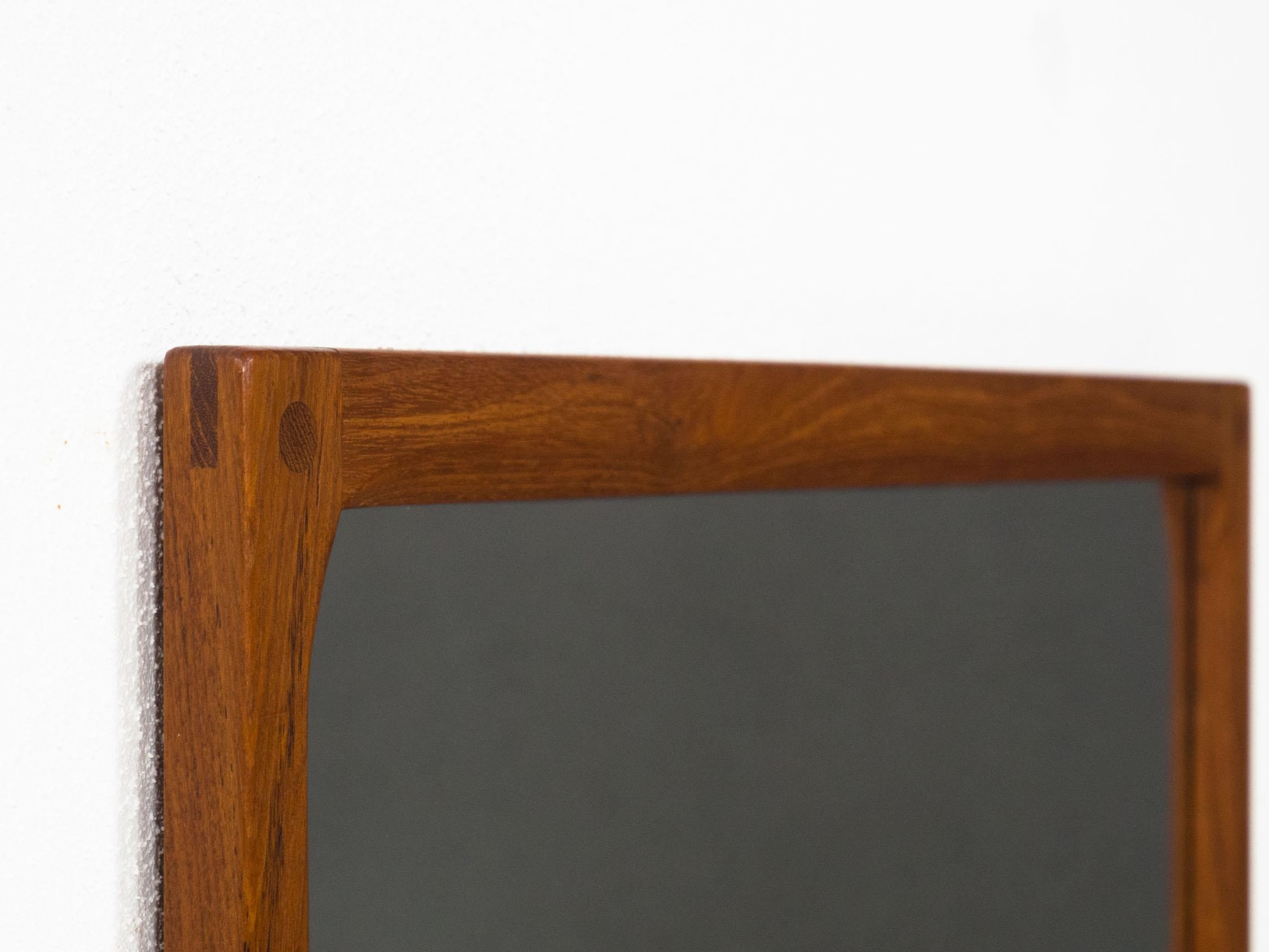 Danish design mirror designed by Kai Kristiansen for Aksel Kjersgaard of Odder, Denmark in the 1960s.

This mirror has a frame that is made from solid teak, and has exposed finger joins and visible solid teak plugs.  It's a prime example of a piece
