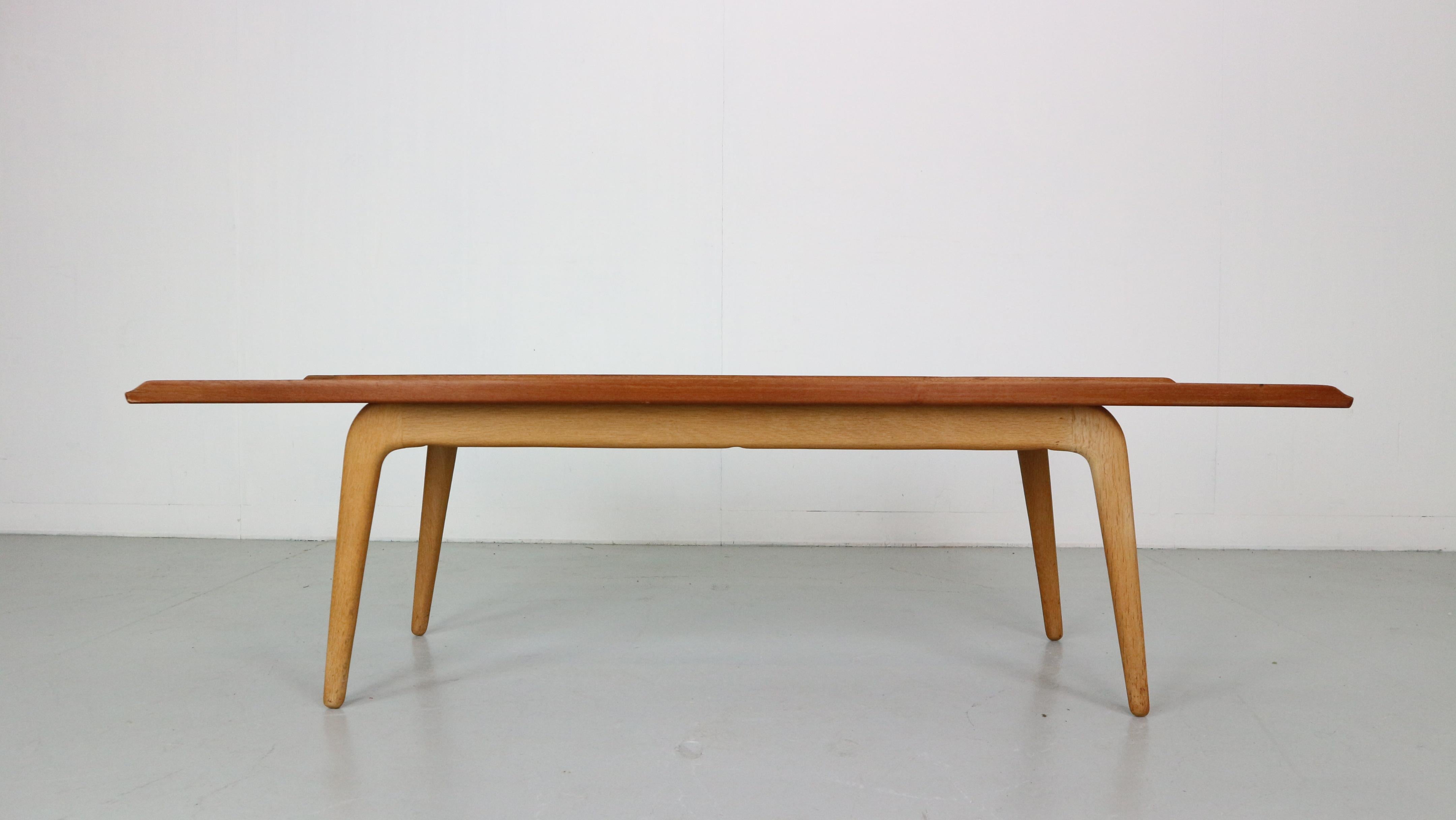This original solid coffee table in teak with 'boomerang' oak legs was designed by the Danish designer Aksel Bender Madsen and manufactured by Bovenkamp in The Netherlands in the 1957s. 
The tabletop features very elegant curved edges on the long