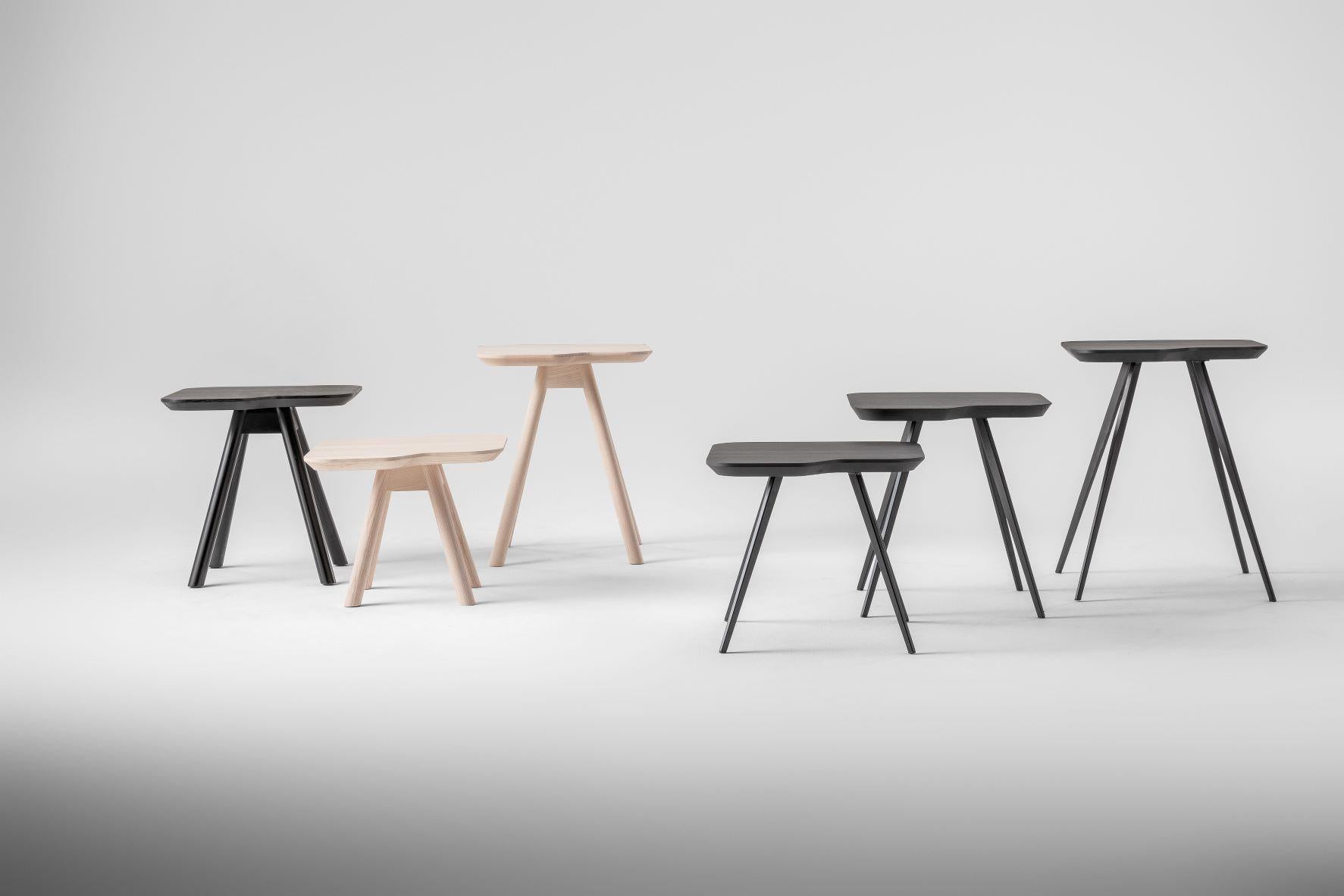 Une collection de tables basses avec un plateau irrégulier et arrondi et des pieds sur tréteaux qui rappellent l'archétype de la table. Les petites tables Aky enrichissent l'espace du salon avec un look agréablement minimal, avec des dimensions