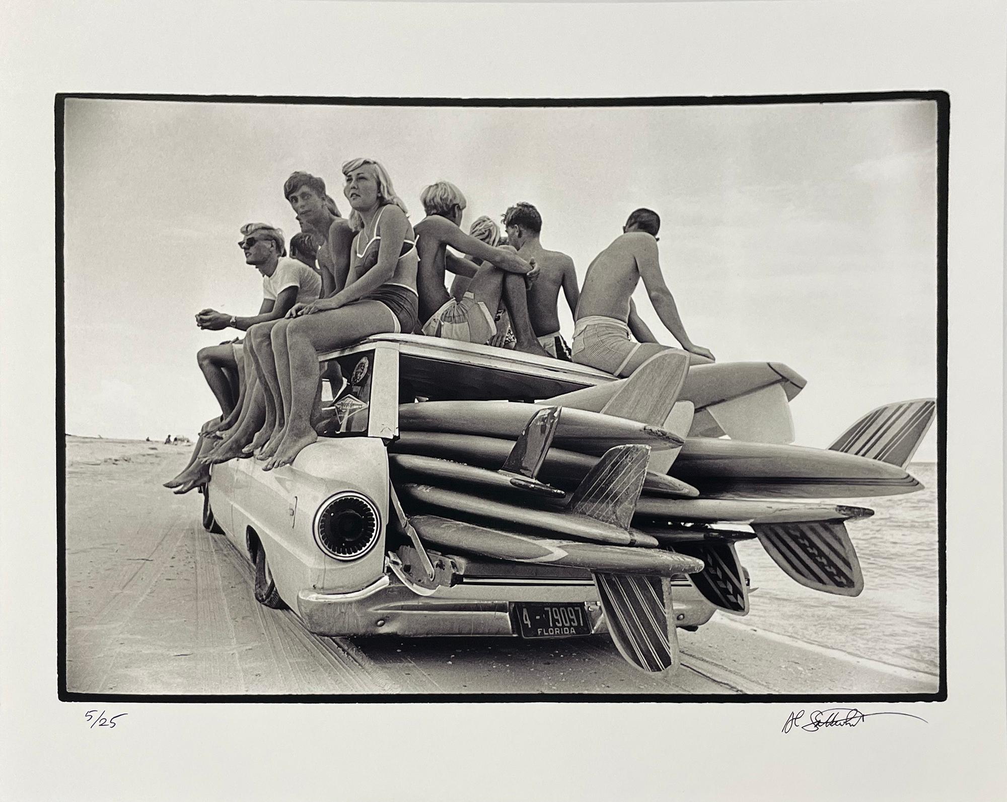 Surf Wagon, St. Petersburg Beach by Al Satterwhite is a 16 x 20 inch archival pigment print, available in an edition of 25. This photograph features a group of teenagers sitting on top of a car filled with surfboards. The image size is 12 x 17 3/4