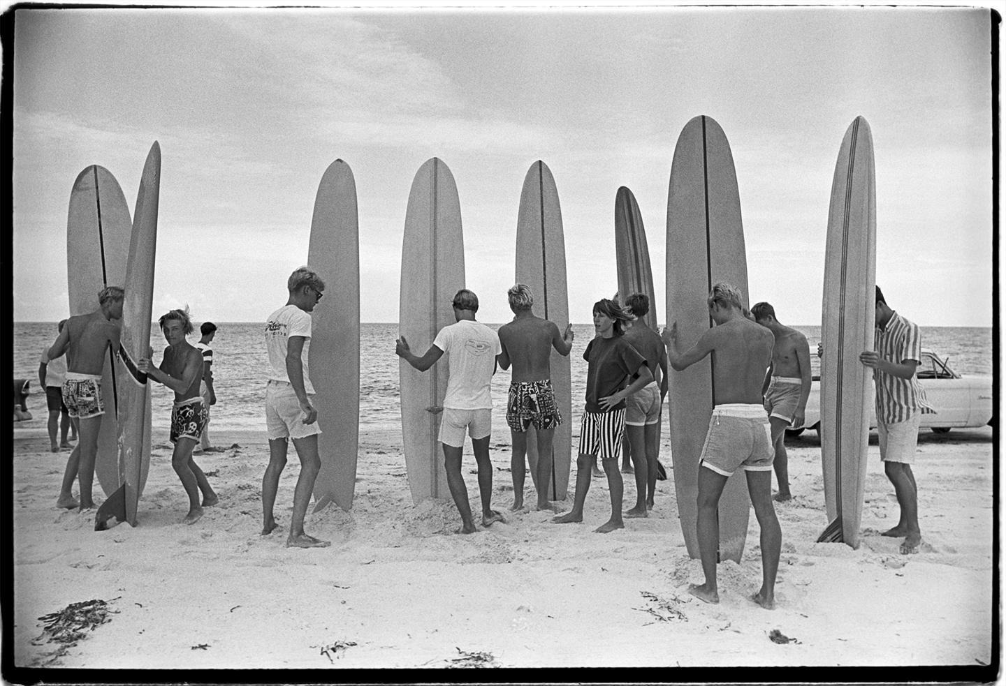 Surfboards in the Sand von Al Satterwhite ist ein 16 x 20 Zoll großer, archivierter Pigmentdruck, der in einer Auflage von 25 Stück erhältlich ist. Dieses Foto zeigt eine Gruppe Jugendlicher mit ihren Surfbrettern im Sand, die darauf warten, ins