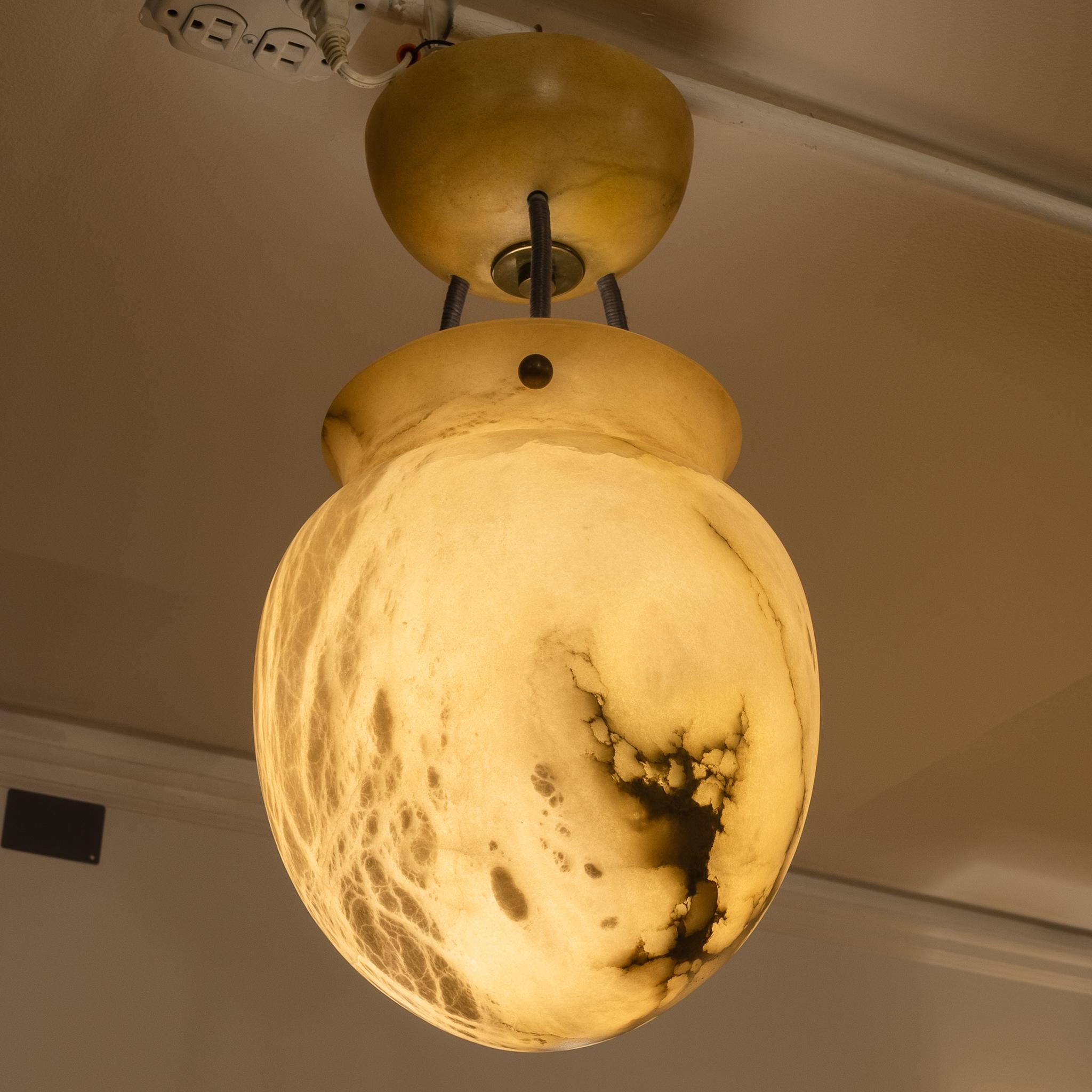 Una lampada vintage realizzata in alabastro egiziano sabbioso. Questo sofisticato apparecchio a forma di anfora incarna una forma classica senza tempo. La pietra naturale presenta eleganti venature nere di mineralizzazione che creano un effetto
