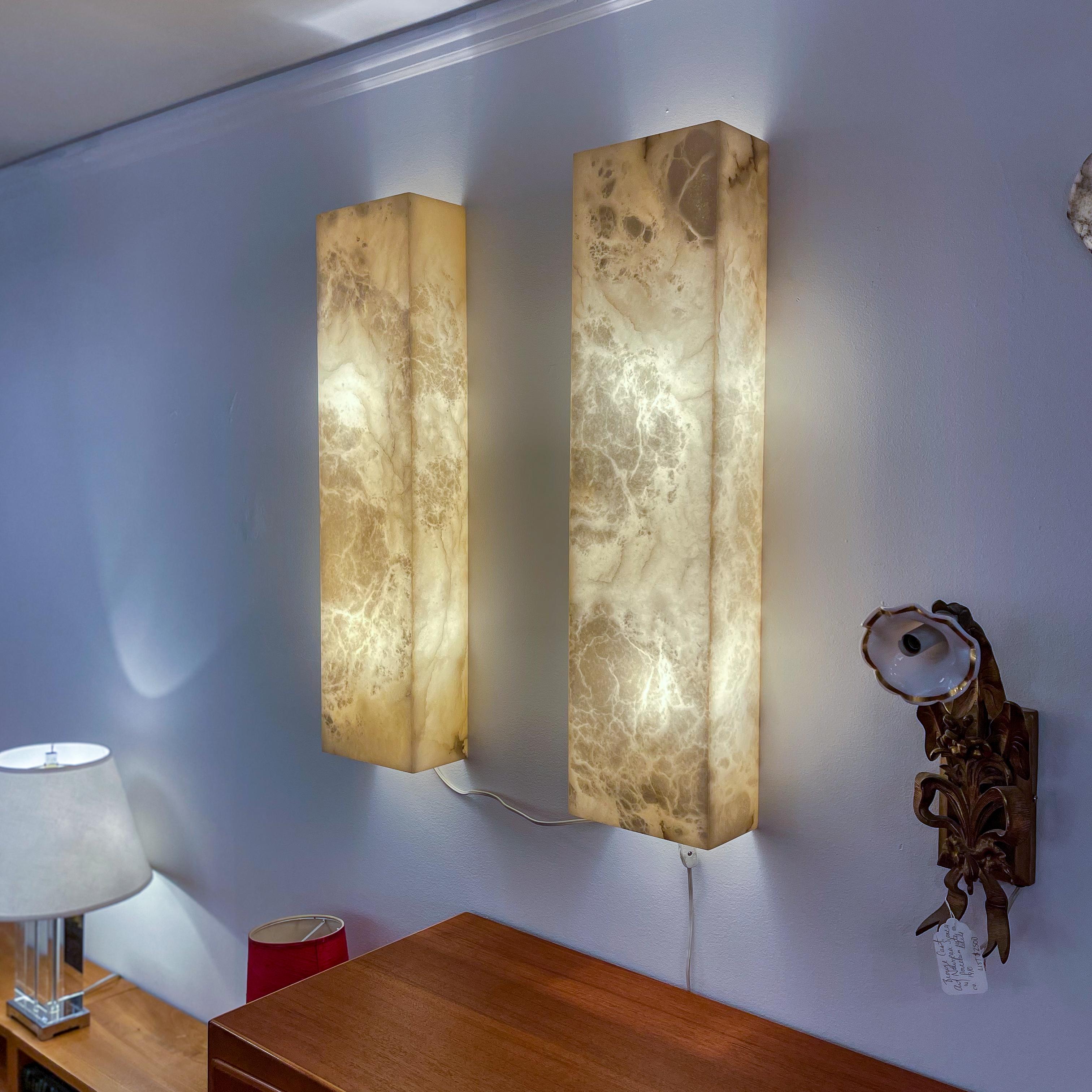 Illuminate your space with this pair of alabaster wall sconces.  Light filters through the stone naturally, juxtaposed with the sharp modernistic shape of the fixture. Each one mounts two 60W dimmable LED lightbulbs and includes everything needed