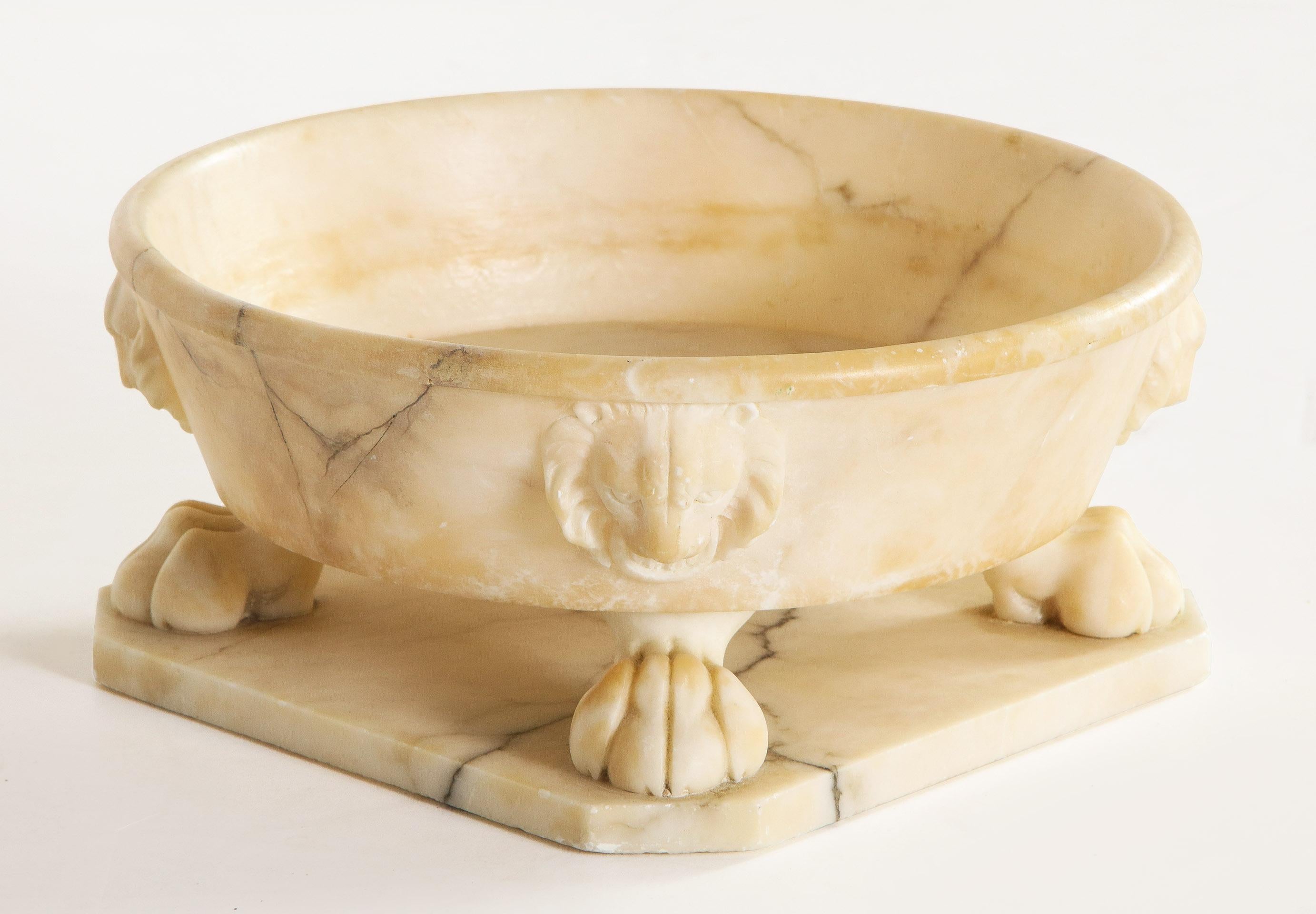 Neoclassic style alabaster bowl

The round alabaster bowl with lions heads on four sides over a corresponding lion paw all on a square base.
