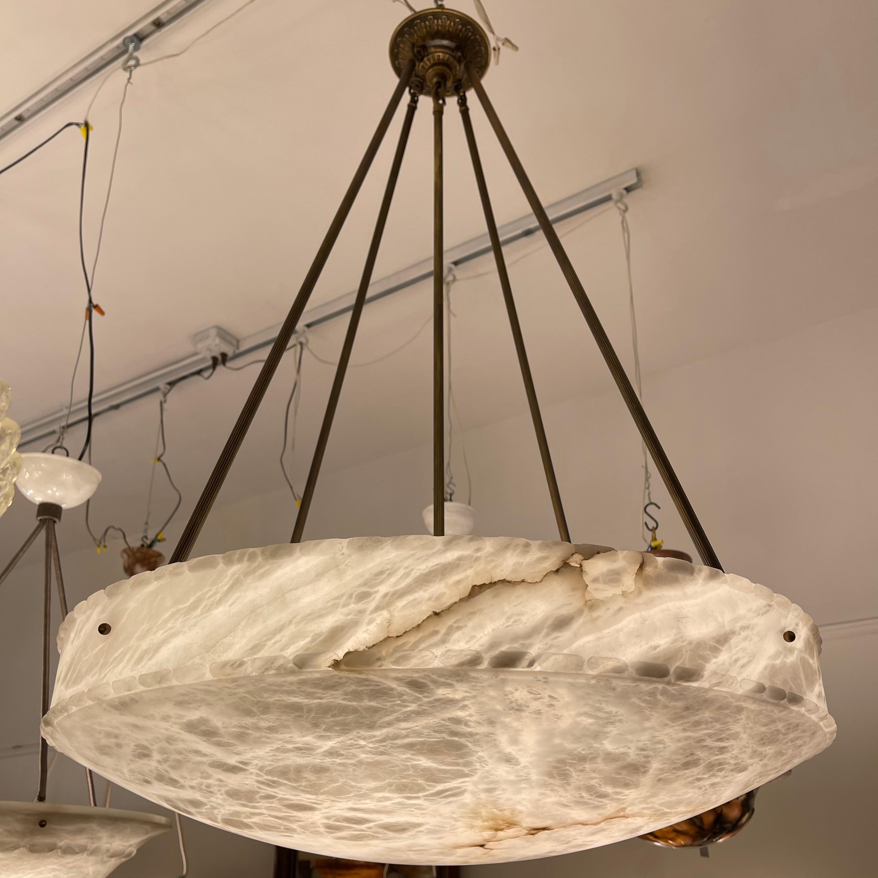 A large scale alabaster dish with gorgeous mineralization, mostly white with flecks of cloudy grey streaking across the face. Suspended on elegant brass rods from a matching brass canopy. Overall height is 45