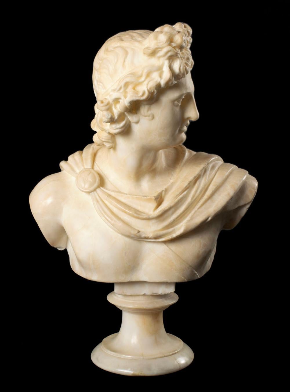 Italienische Alabasterbüste aus dem 19. Jahrhundert von Apollo, dem griechischen Gott der Kunst, Medizin und Musik. Die Büste aus weißem Alabaster ist aufwendig gestaltet und zeigt den griechischen Gott, der nach links blickt und einen Umhang über