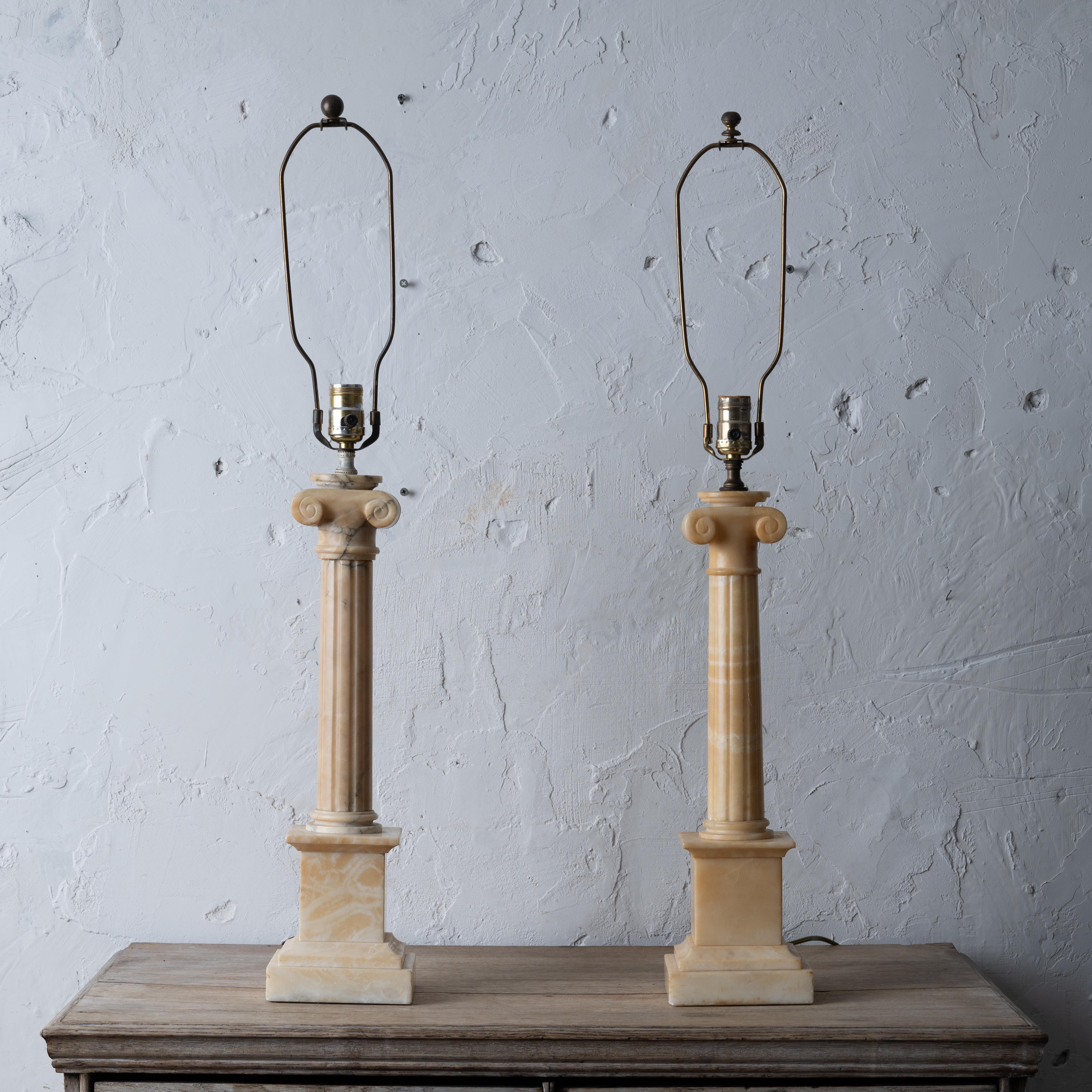 A pair of Italian alabaster table lamps, mid 20th century.
Columnar-form with tapering fluted columns on round feet with ionic capitals, elevated by square plinths.

5 ½ inches wide by 20 inches tall (top of alabaster); total height: 33 ¼ inches