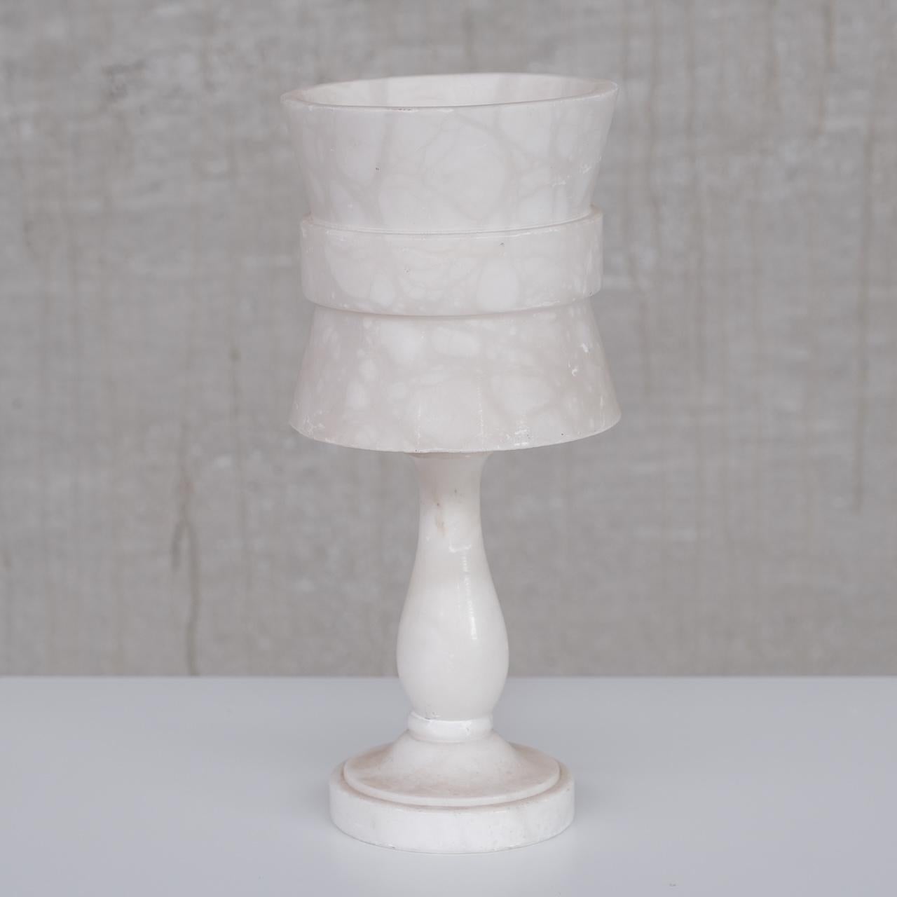An alabaster table lamp. 

France, c1950s. 

Sourced in a cluster of seven varied style alabaster lamps. 

Price is for the single lamp. 

Some scuffs and wear commensurate with age but generally good condition. 

Since re-wired and PAT