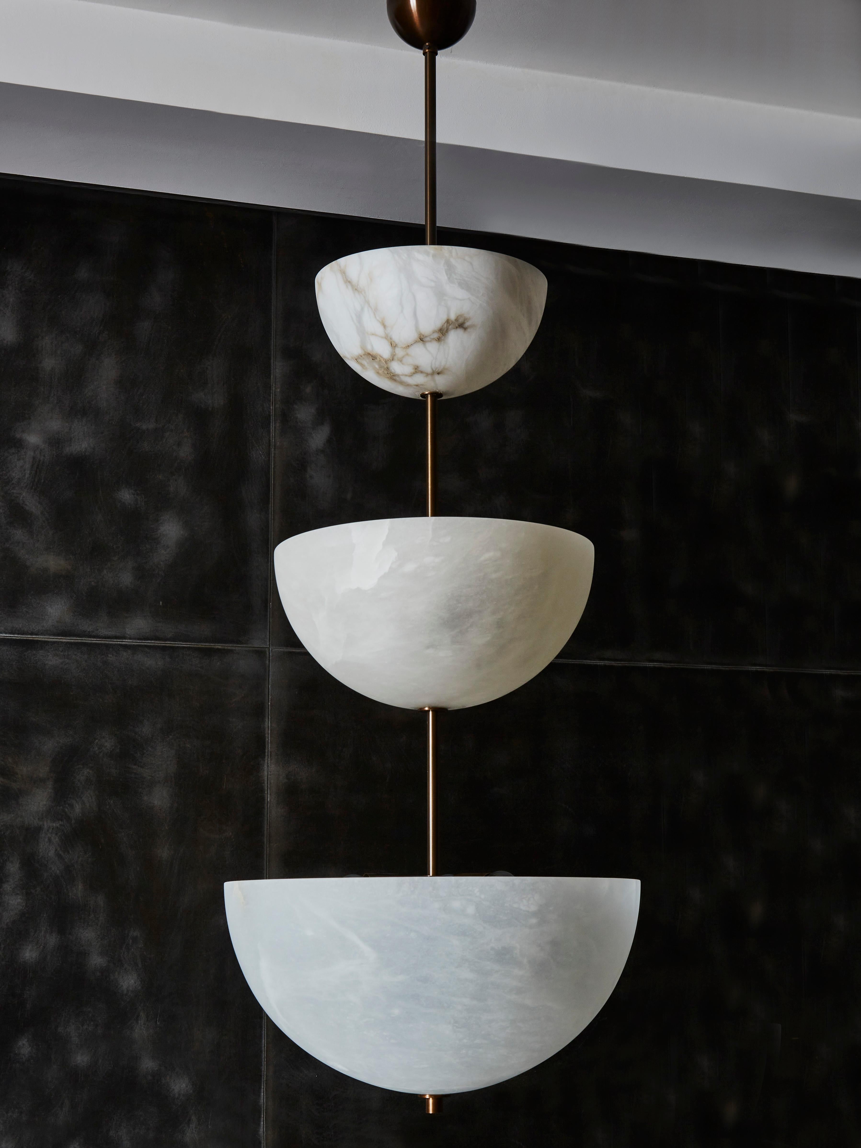 Three alabaster half spheres of different sizes are vertically stacked on each other with a brass stem.

Each bowl has several light sources inside.

Original design by Glustin Luminaires.